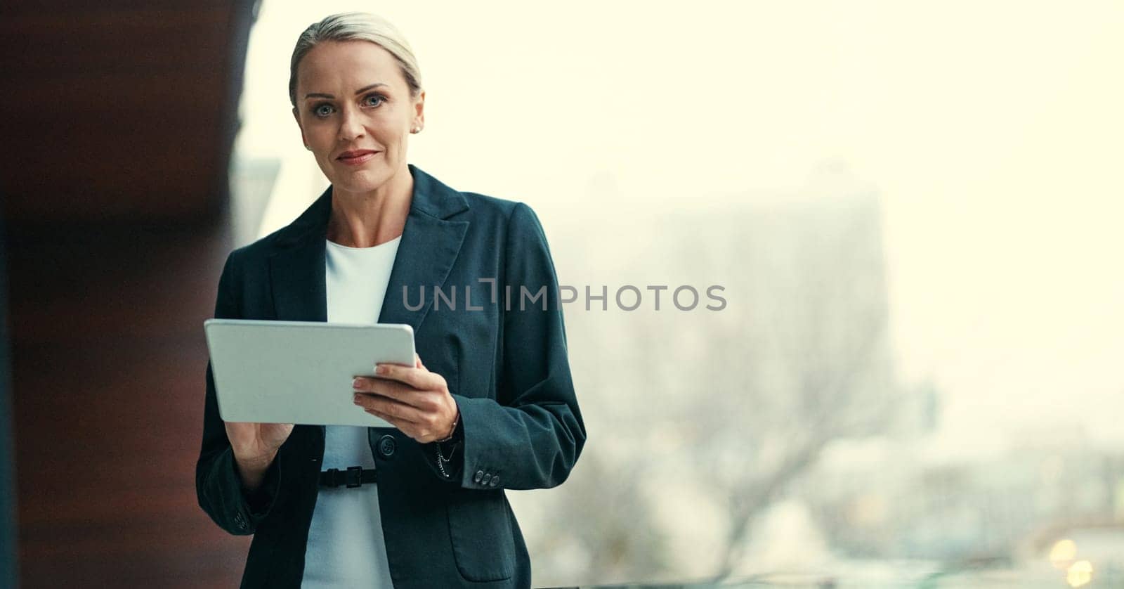 Im as ambitious as Ive ever been. Cropped portrait of an attractive mature businesswoman using her tablet while standing on the balcony of her office. by YuriArcurs
