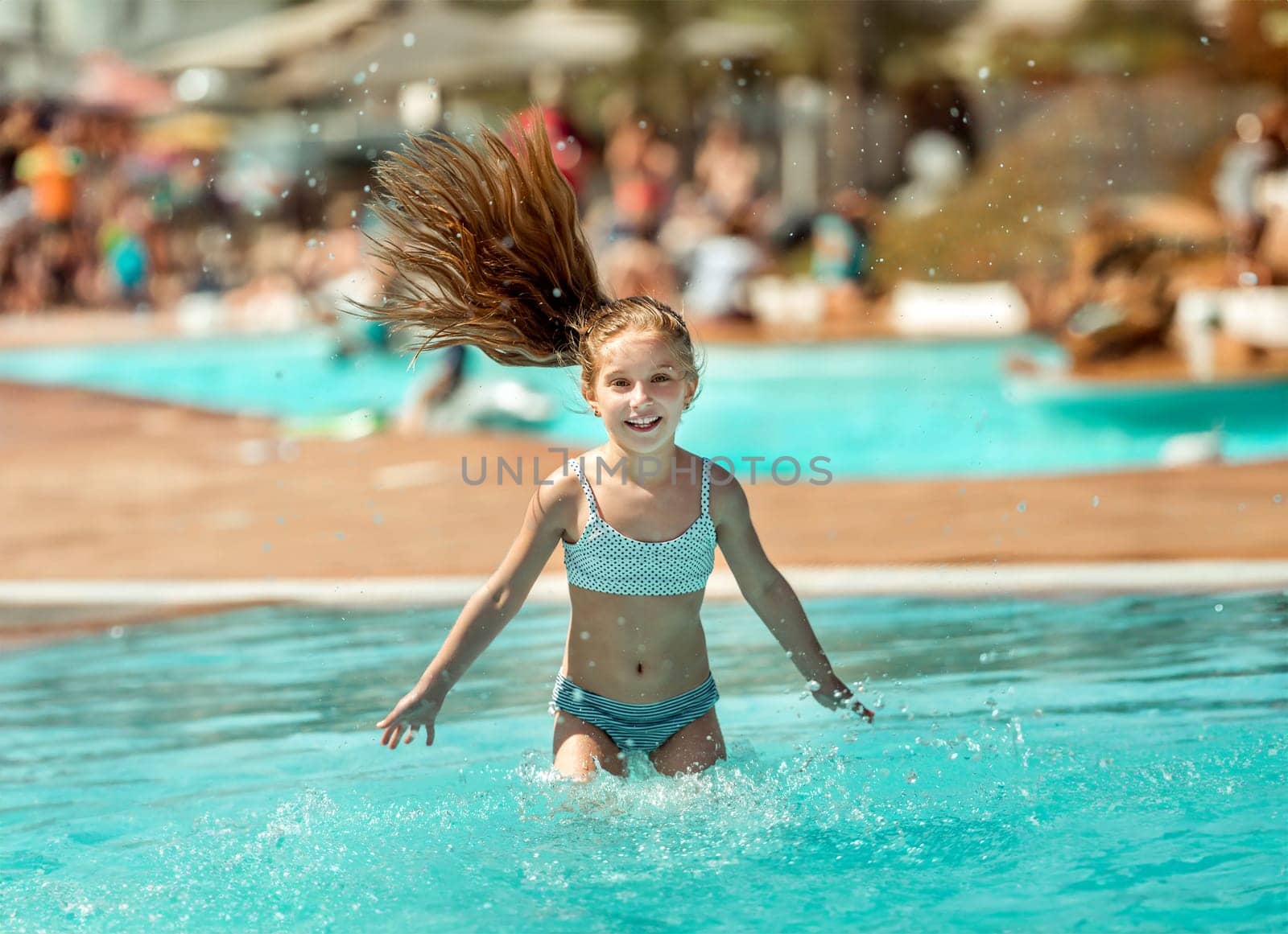 Portrait of lovely little teenage girl ressting on the edge of swimming pool and squinting her eyes because of the bright sun