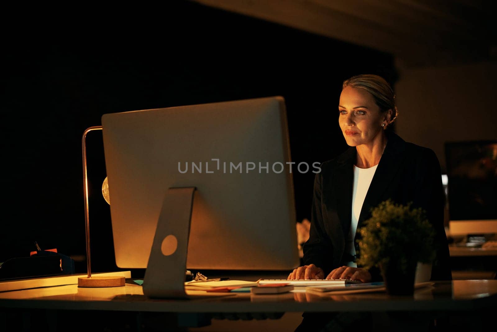 Working late to perfect the details on my project. a mature businesswoman working late at the office. by YuriArcurs