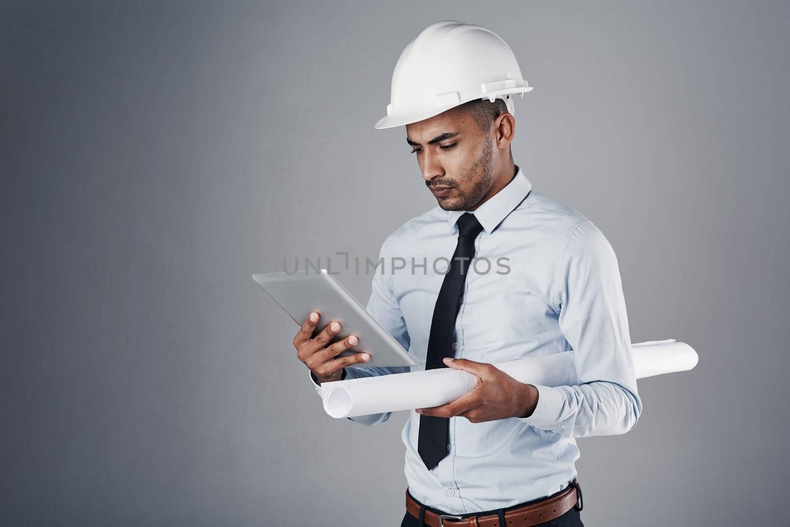 The right tools make every job easier. a well-dressed civil engineer using his tablet while standing in the studio. by YuriArcurs