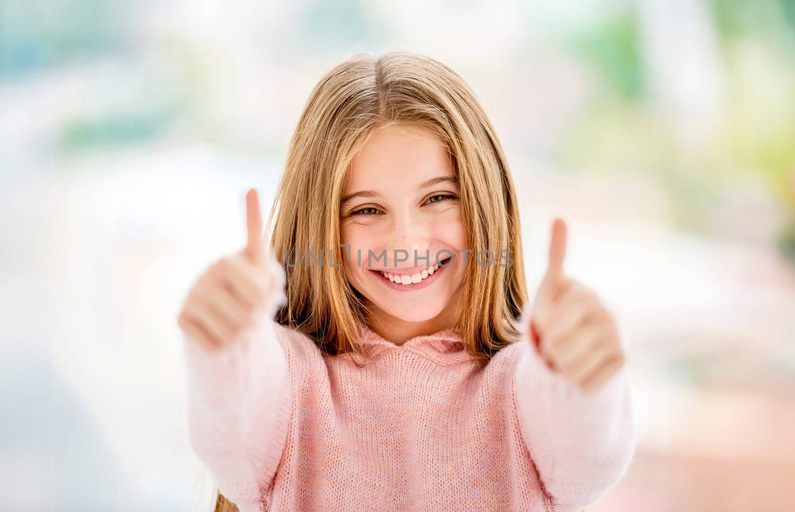 Cute little girl showing sign super with both thumbs