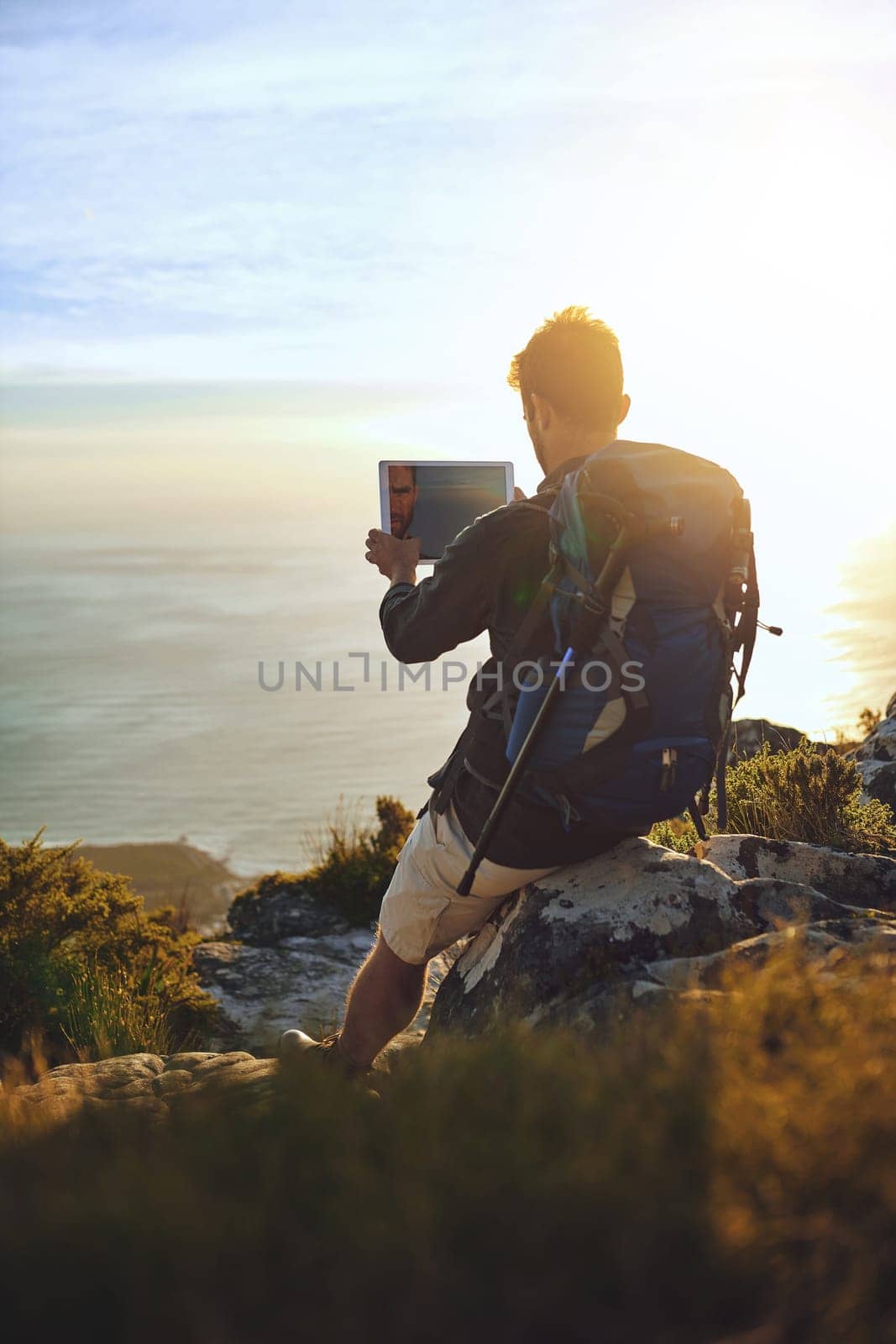 Its an adults playground. a young man using a digital tablet while hiking up a mountain. by YuriArcurs