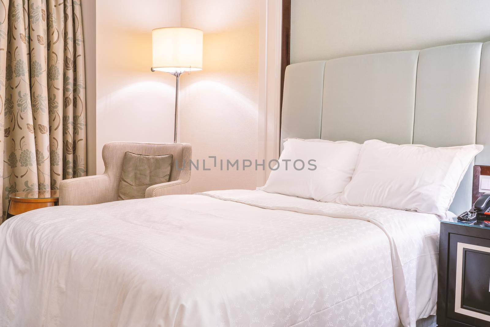 Clean and cozy modern hotel bedroom interior, warm tone room with a standing lamp, linen sofa with a cushion, design concept of luxury travel, close up. by ROMIXIMAGE