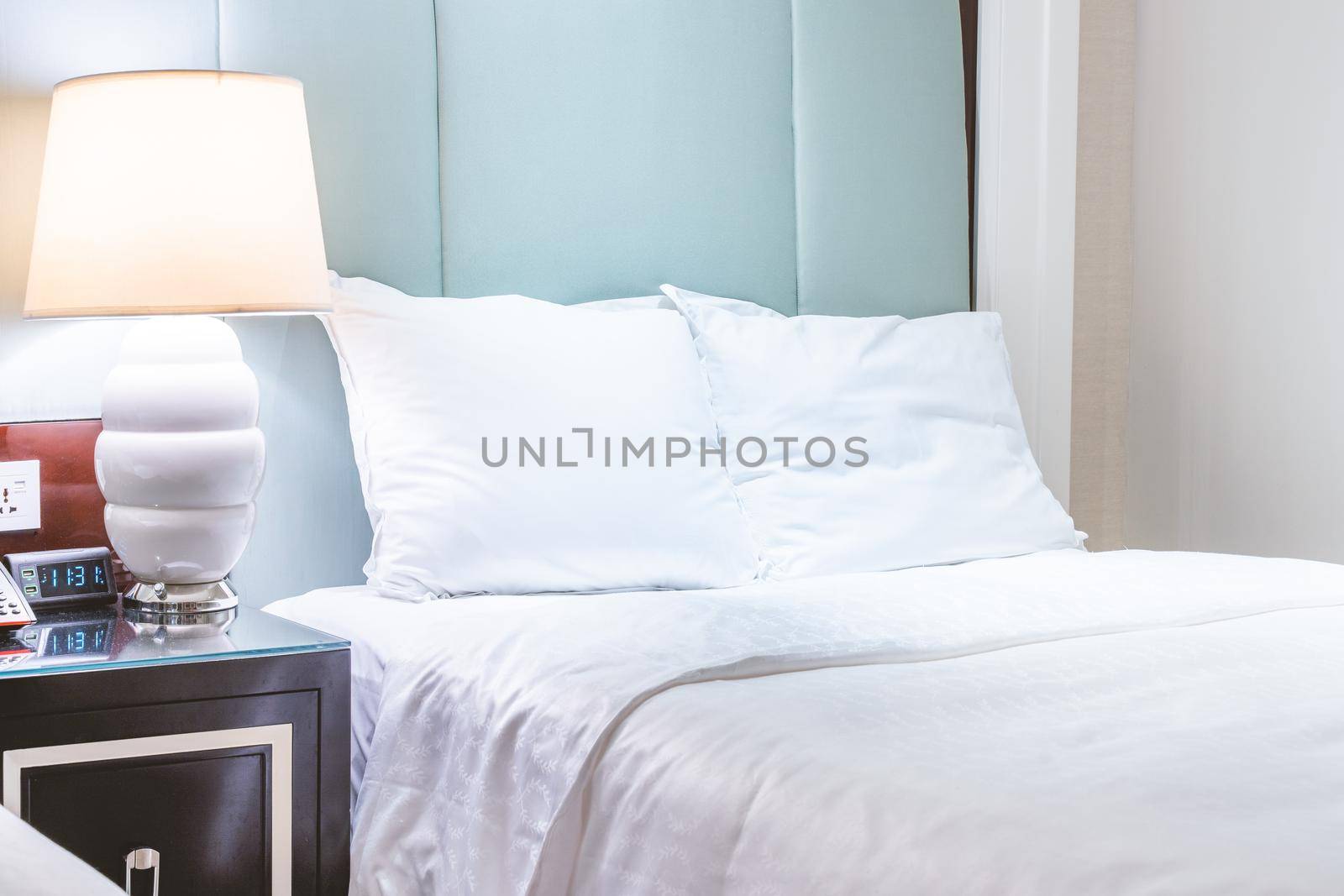 Clean and cozy modern hotel bedroom interior, warm tone room with a standing lamp, linen sofa with a cushion, design concept of luxury travel, close up.