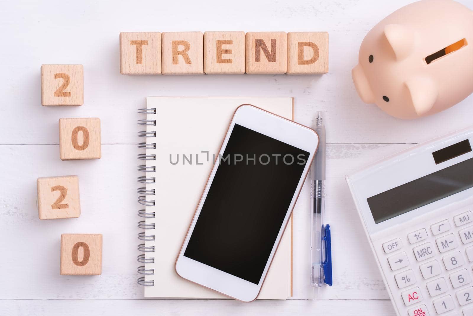 2020 goal, finance plan abstract design concept, wood blocks on white table background with piggy bank, cell phone, top view, flat lay, copy space.