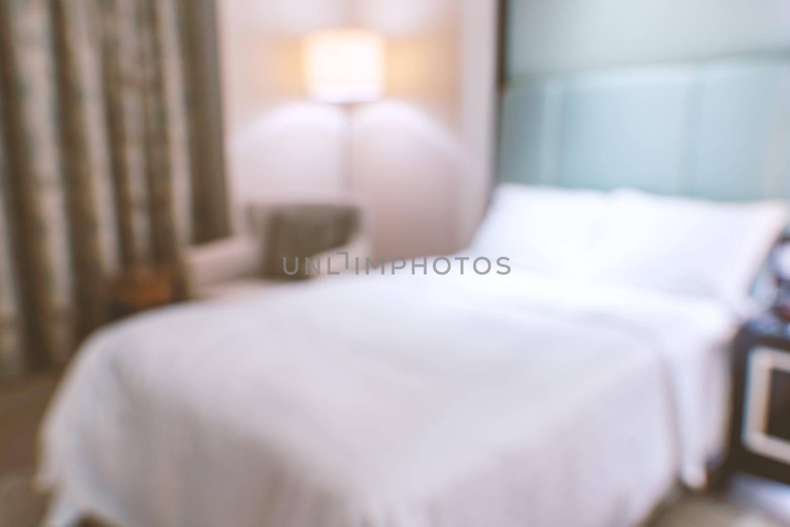 Clean and cozy modern hotel bedroom interior with double bed, abstract defocused blur with bokeh background, design concept of luxury trip.