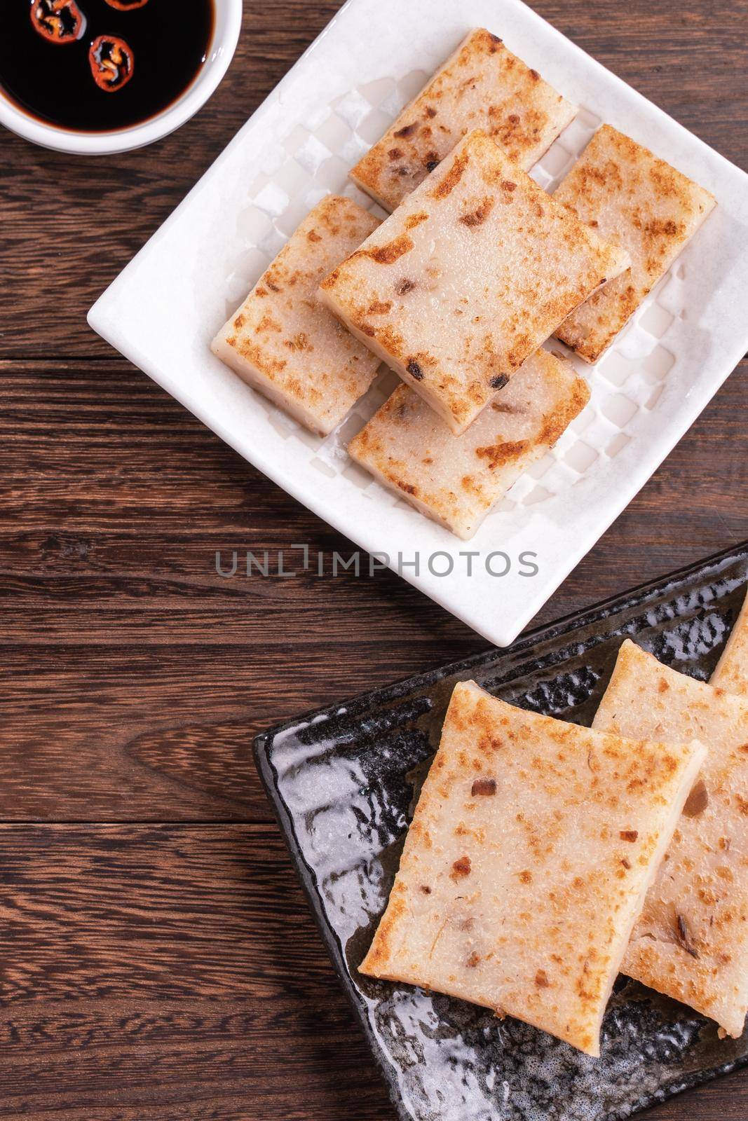 Delicious turnip cake, Chinese traditional radish cake in restaurant with soy sauce for new year's dishes, close up, copy space, top view, flat lay.