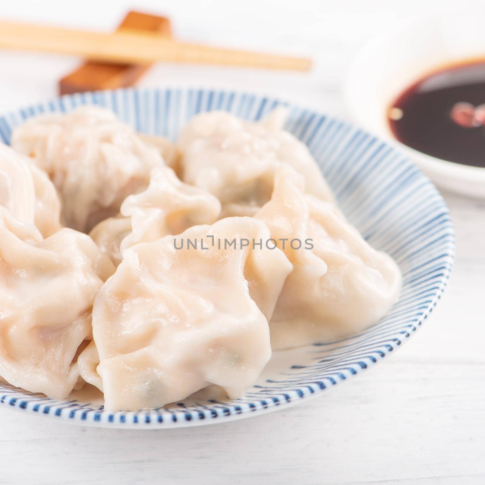 Fresh, delicious boiled pork, shrimp gyoza dumplings on white background with soy sauce and chopsticks, close up, lifestyle. Homemade design concept.