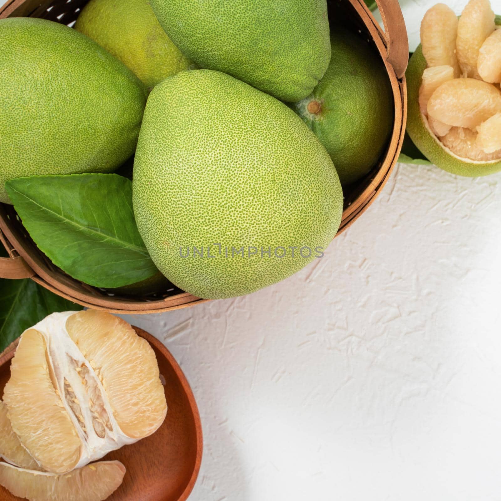 Fresh pomelo, pummelo, grapefruit, shaddock on white cement background in bamboo basket. Autumn seasonal fruit, top view, flat lay, tabletop shot.