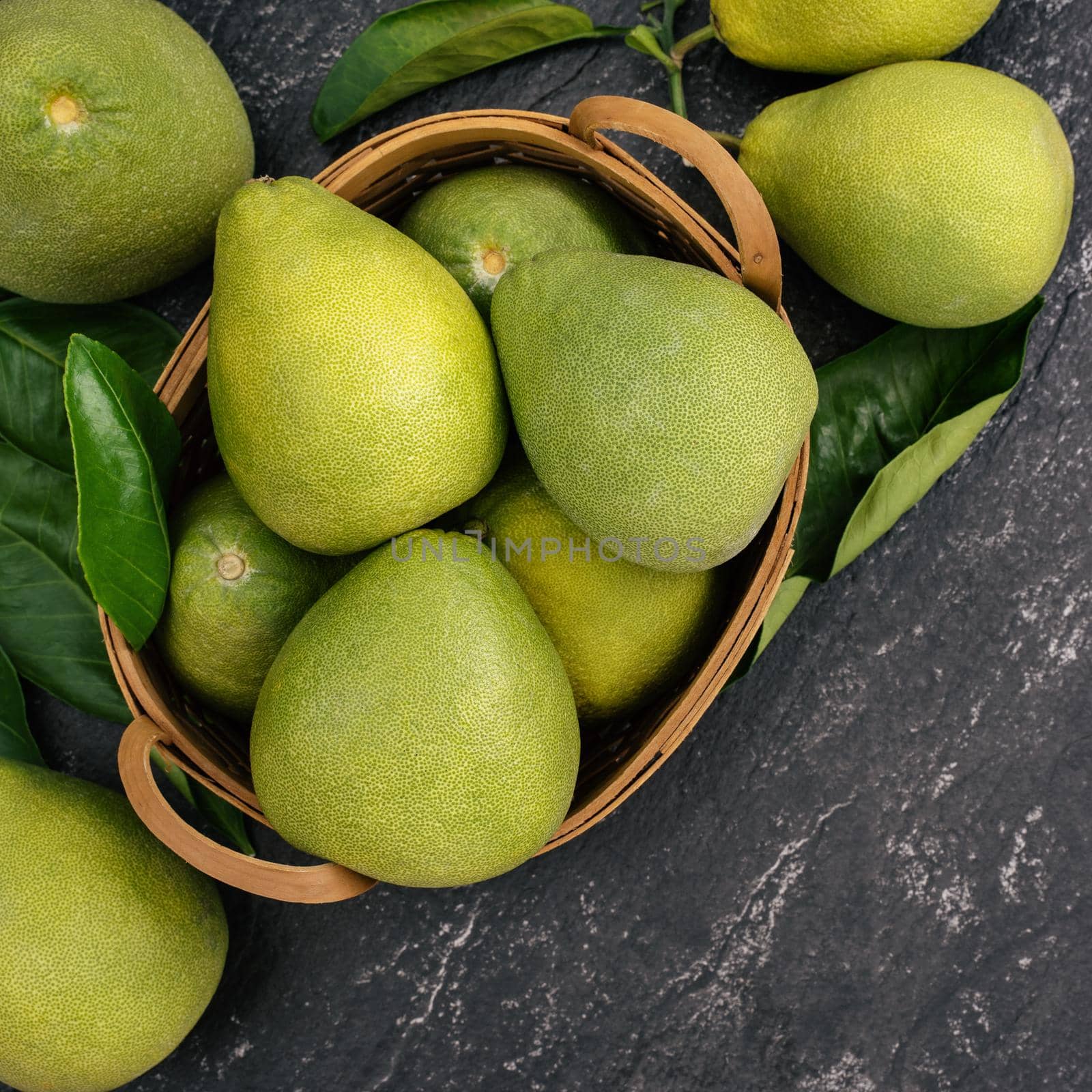 Fresh peeled pomelo, pummelo, grapefruit, shaddock on dark background in bamboo basket. Autumn seasonal fruit, top view, flat lay, tabletop shot.