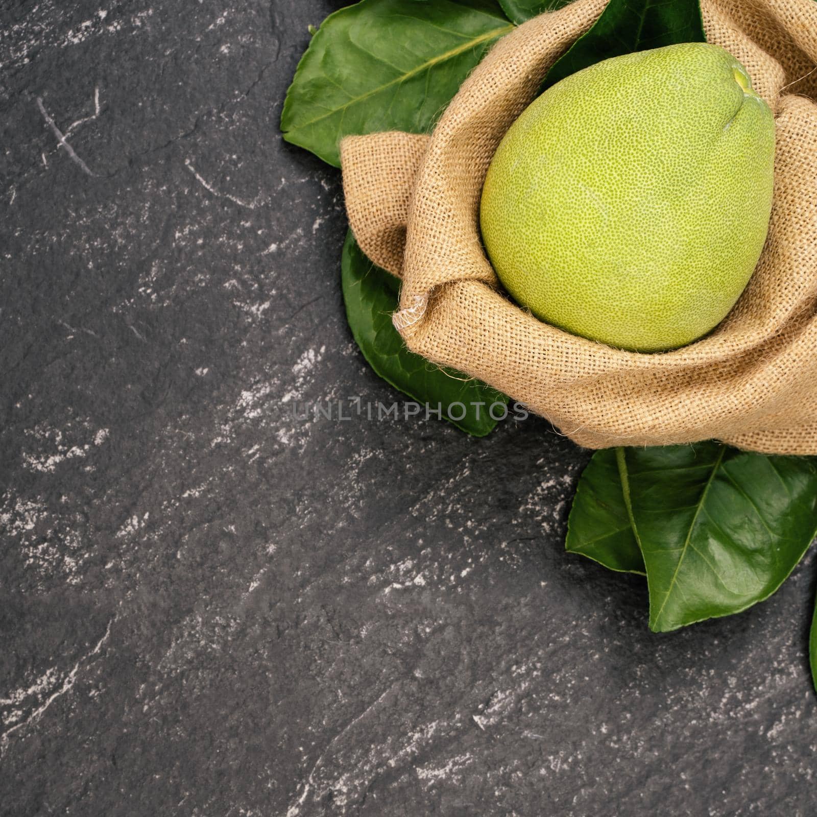 Fresh peeled pomelo, pummelo, grapefruit, shaddock on dark background in bamboo basket. Autumn seasonal fruit, top view, flat lay, tabletop shot.