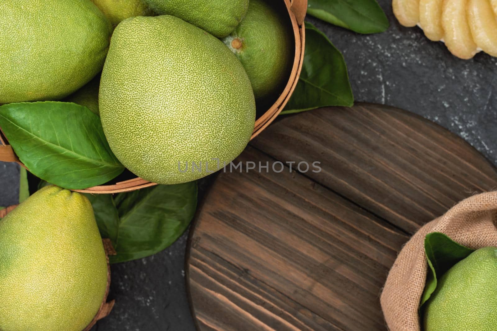 Fresh peeled pomelo, pummelo, grapefruit, shaddock on dark background in bamboo basket. Autumn seasonal fruit, top view, flat lay, tabletop shot.