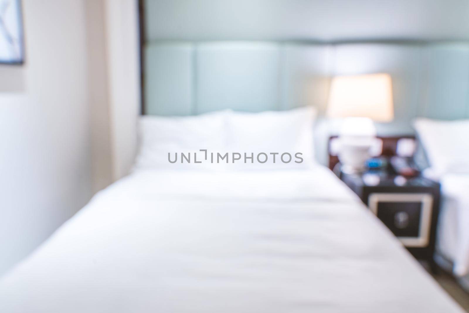 Clean and cozy modern hotel bedroom interior with double bed, abstract defocused blur with bokeh background, design concept of luxury trip.