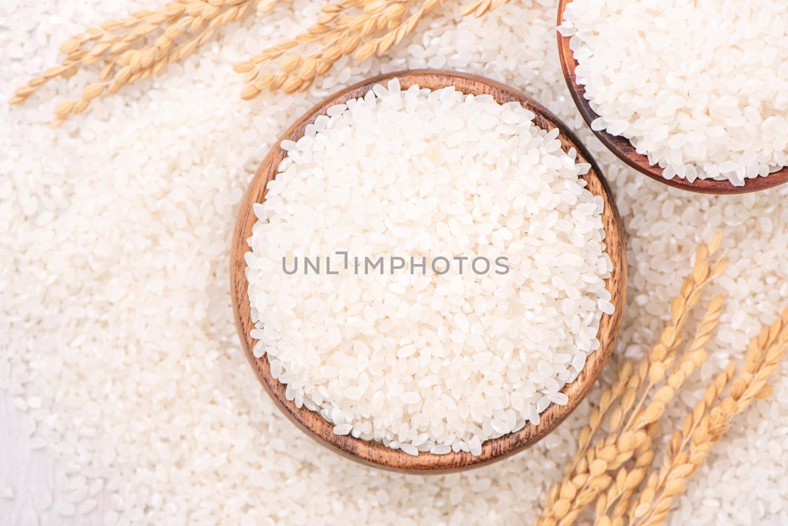 Raw white polished milled edible rice crop on white background in brown bowl, organic agriculture design concept. Staple food of Asia, close up.