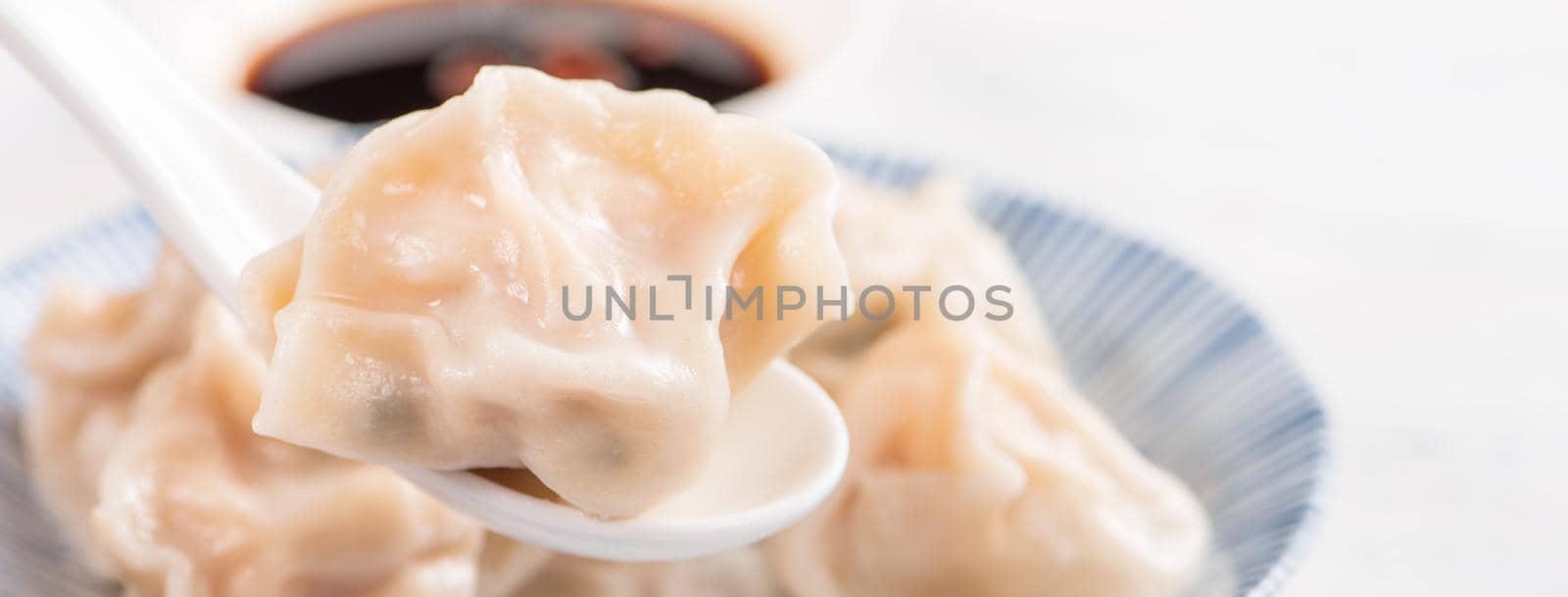 Fresh, delicious boiled pork, shrimp gyoza dumplings on white background with soy sauce and chopsticks, close up, lifestyle. Homemade design concept.