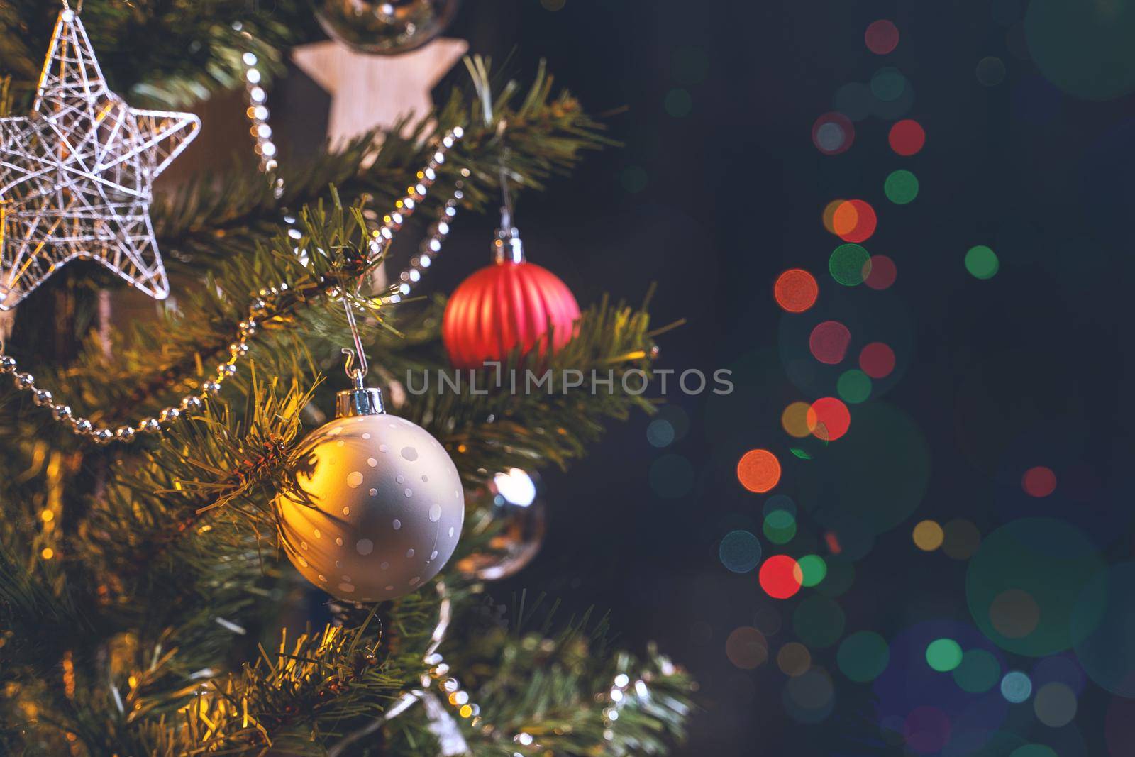Beautiful Christmas decor concept, bauble hanging on the Christmas tree with sparkling light spot, blurry dark black background, macro detail, close up.