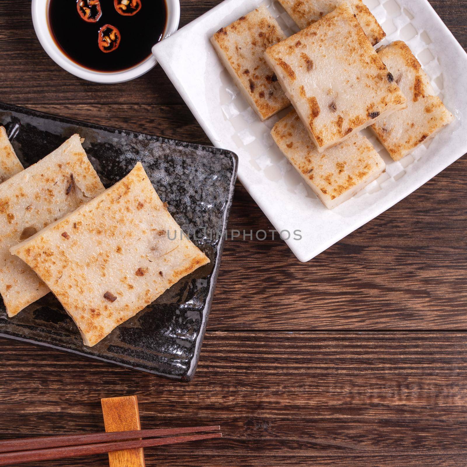 Delicious turnip cake, Chinese traditional radish cake in restaurant with soy sauce for new year's dishes, close up, copy space, top view, flat lay. by ROMIXIMAGE