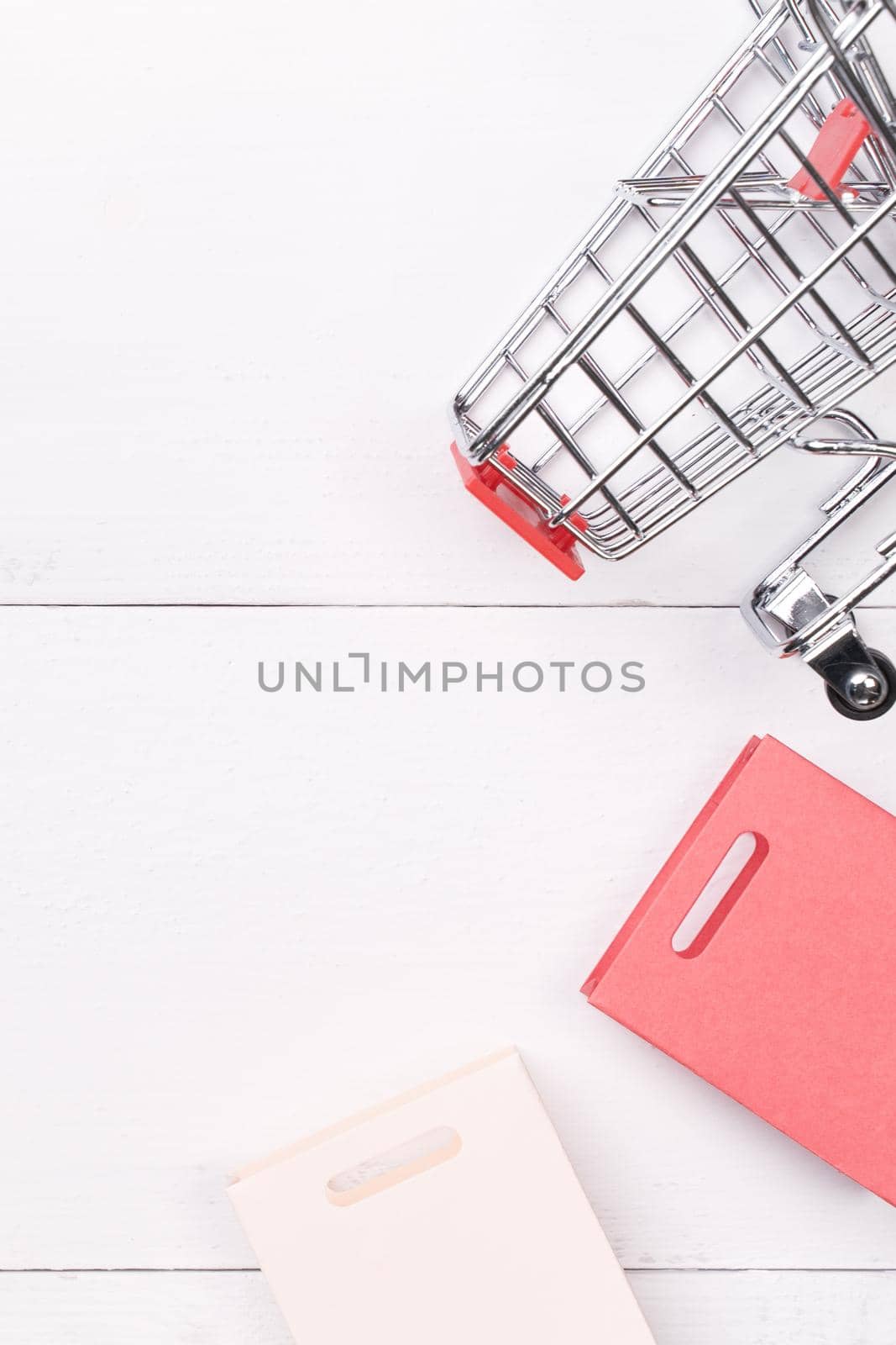 Abstract design element,annual sale,shopping season concept,mini cart with colorful paper bag on white wooden table background,top view,flat lay by ROMIXIMAGE