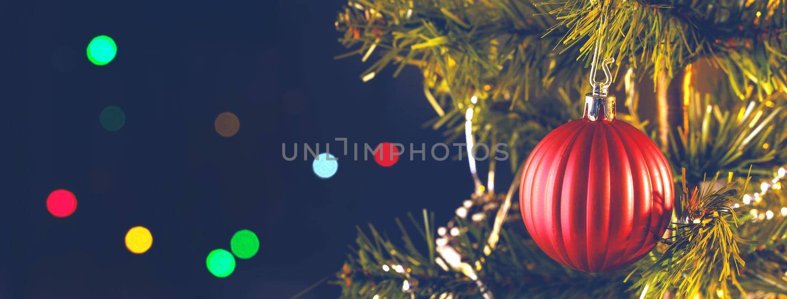 Beautiful Christmas decor concept, bauble hanging on the Christmas tree with sparkling light spot, blurry dark black background, macro detail, close up.