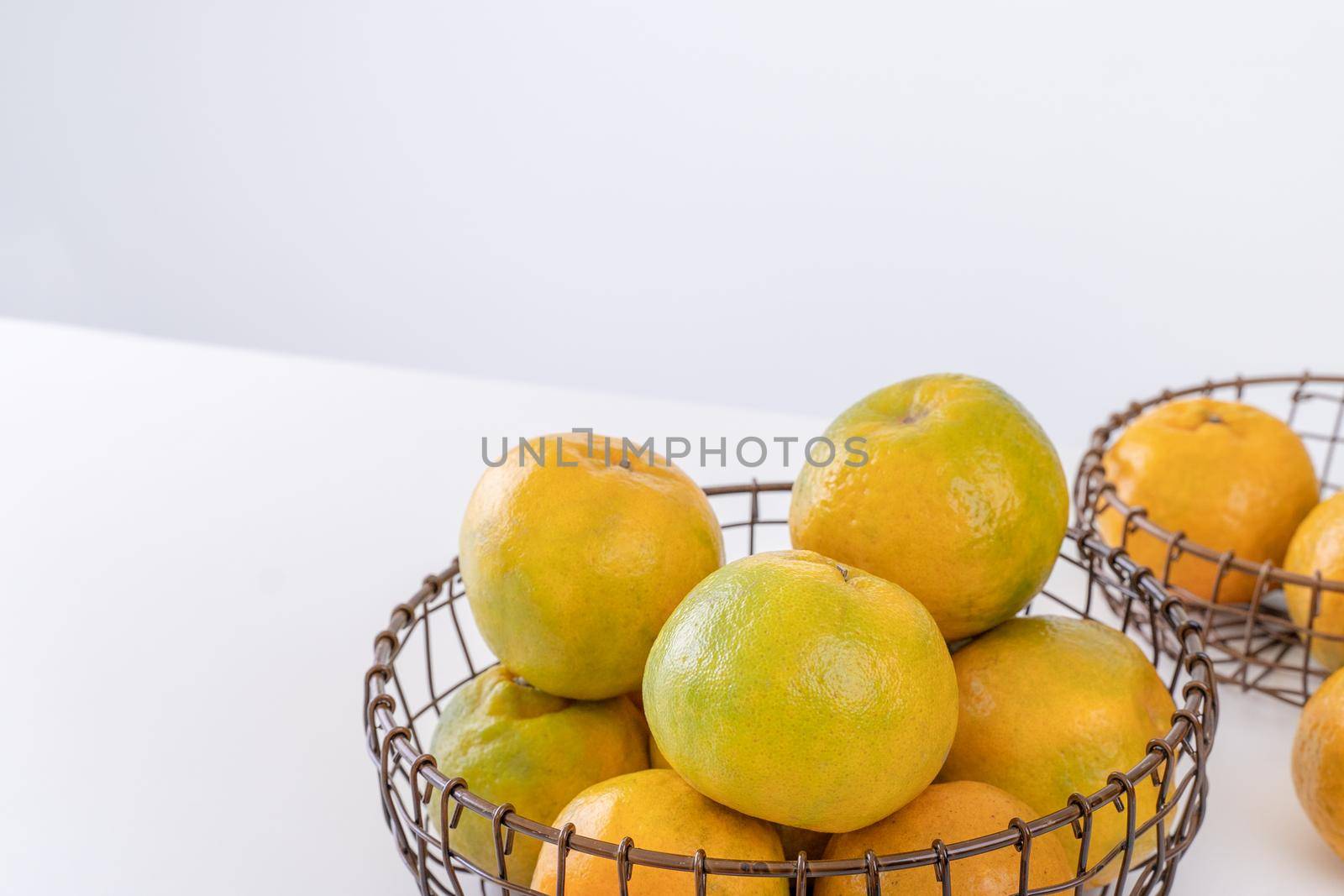 Beautiful peeled tangerines in a plate and metal basket isolated on bright white clean table in a modern contemporary kitchen island, close up.