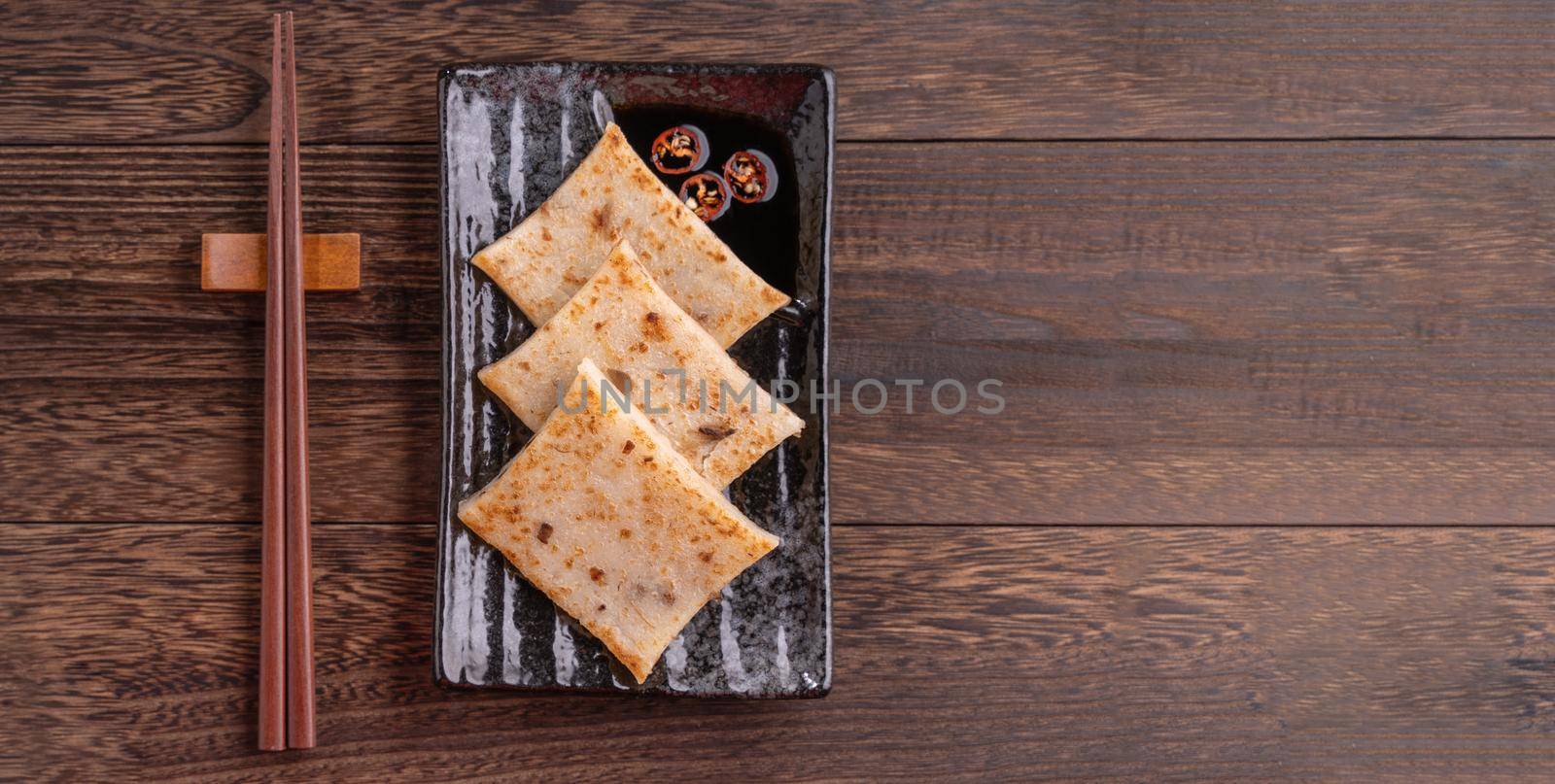 Delicious turnip cake, Chinese traditional radish cake in restaurant with soy sauce for new year's dishes, close up, copy space, top view, flat lay.