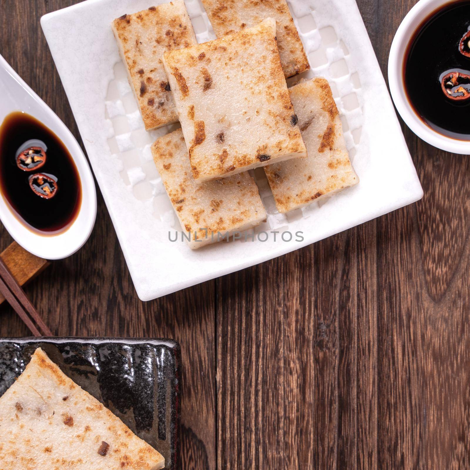 Delicious turnip cake, Chinese traditional radish cake in restaurant with soy sauce for new year's dishes, close up, copy space, top view, flat lay.