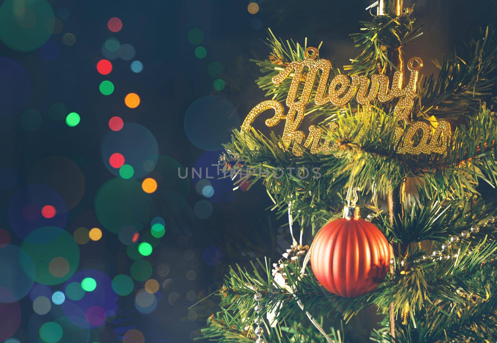 Beautiful Christmas decor concept, bauble hanging on the Christmas tree with sparkling light spot, blurry dark black background, macro detail, close up.