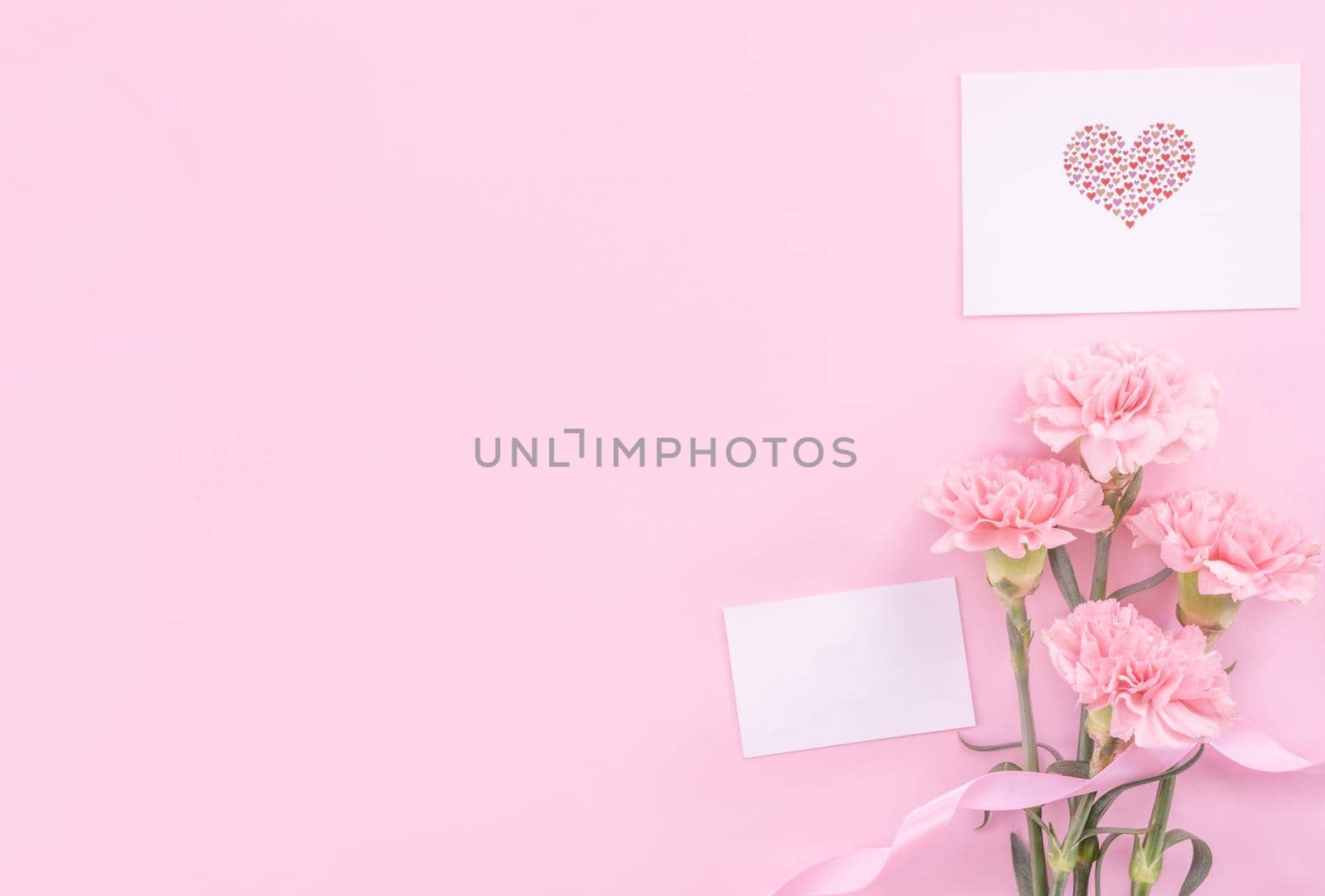 Beautiful, fresh elegant carnation flower bouquet with white greeting thanks gift card isolated on bright pink color background, top view, flat lay concept.