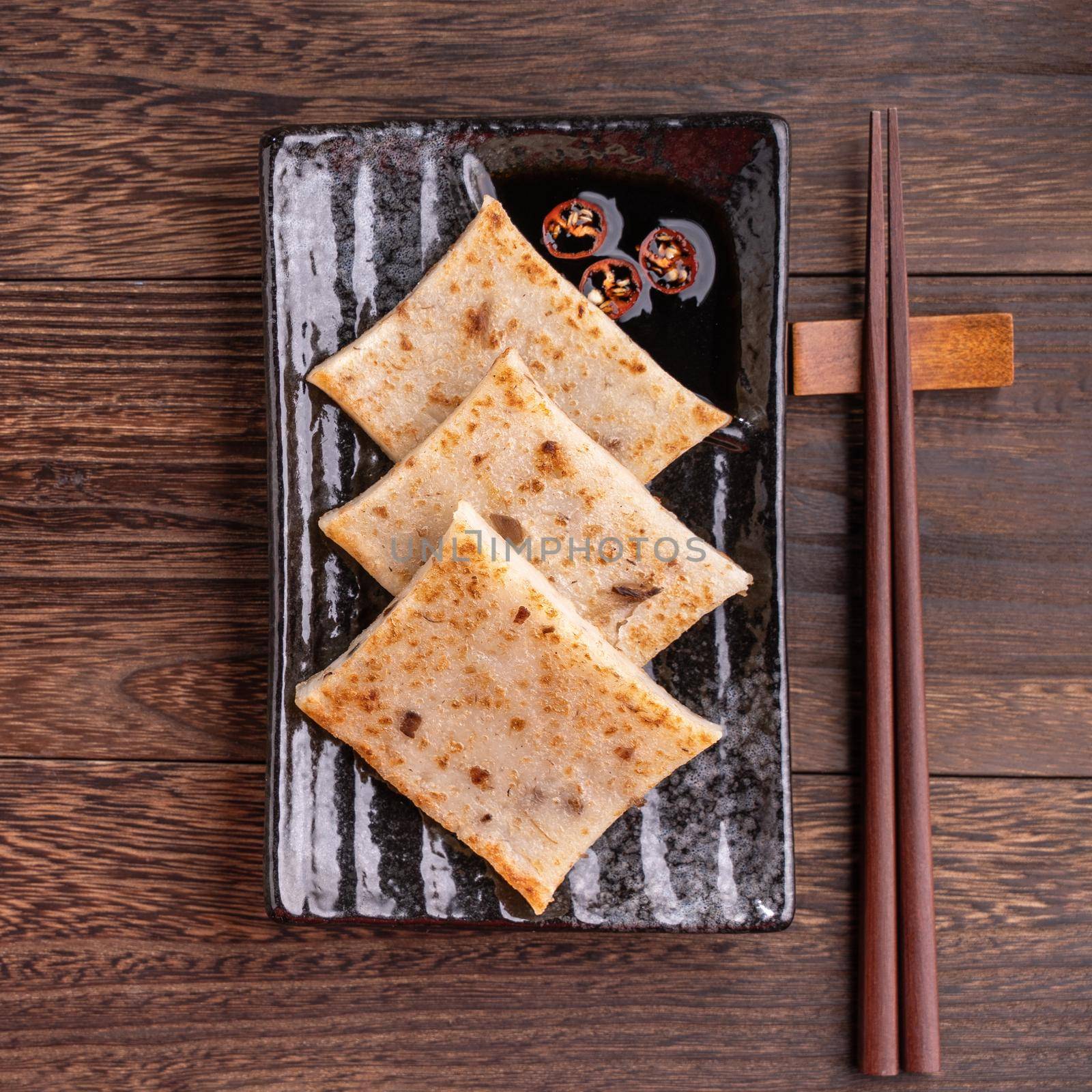 Delicious turnip cake, Chinese traditional radish cake in restaurant with soy sauce for new year's dishes, close up, copy space, top view, flat lay.