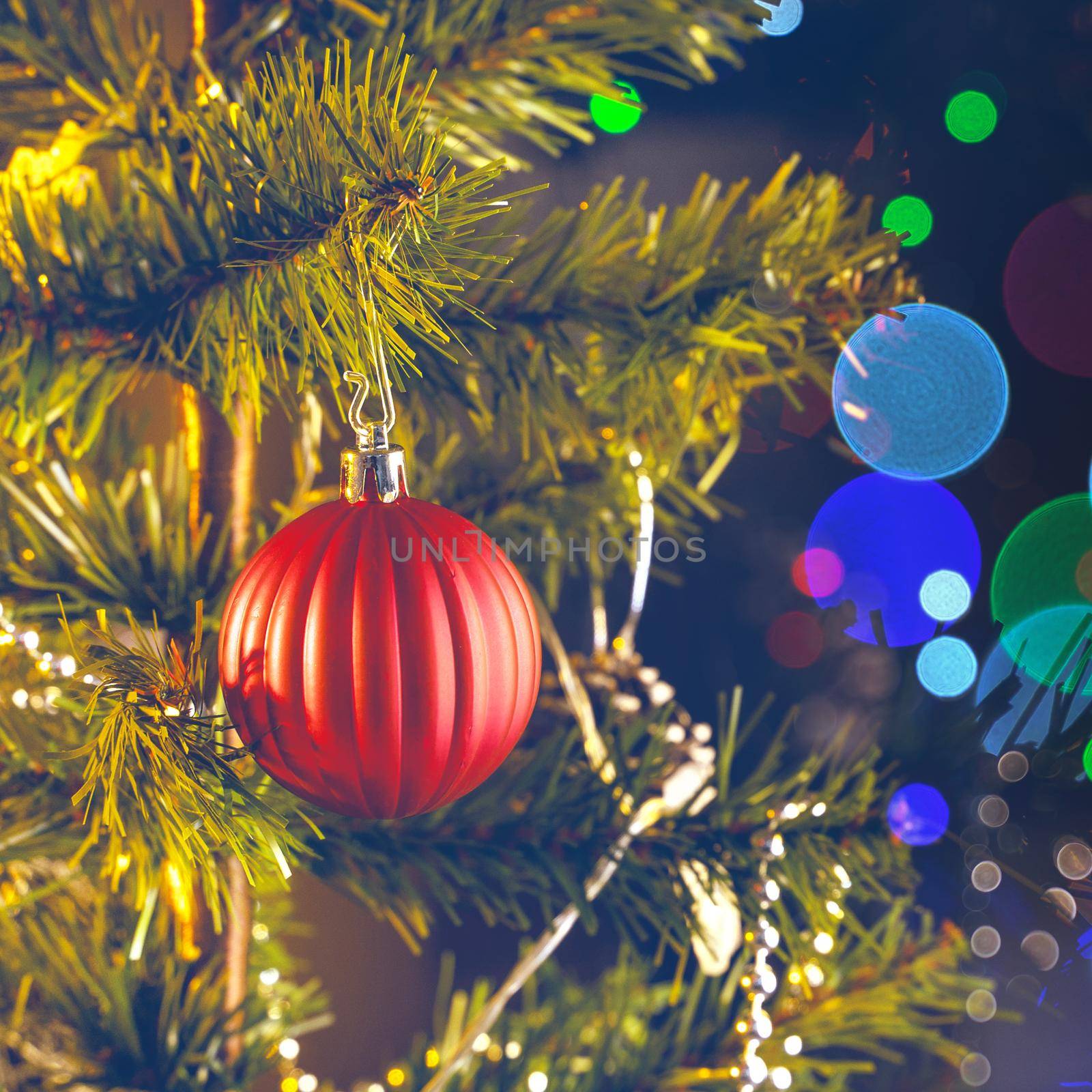 Beautiful Christmas decor concept, bauble hanging on the Christmas tree with sparkling light spot, blurry dark black background, macro detail, close up.