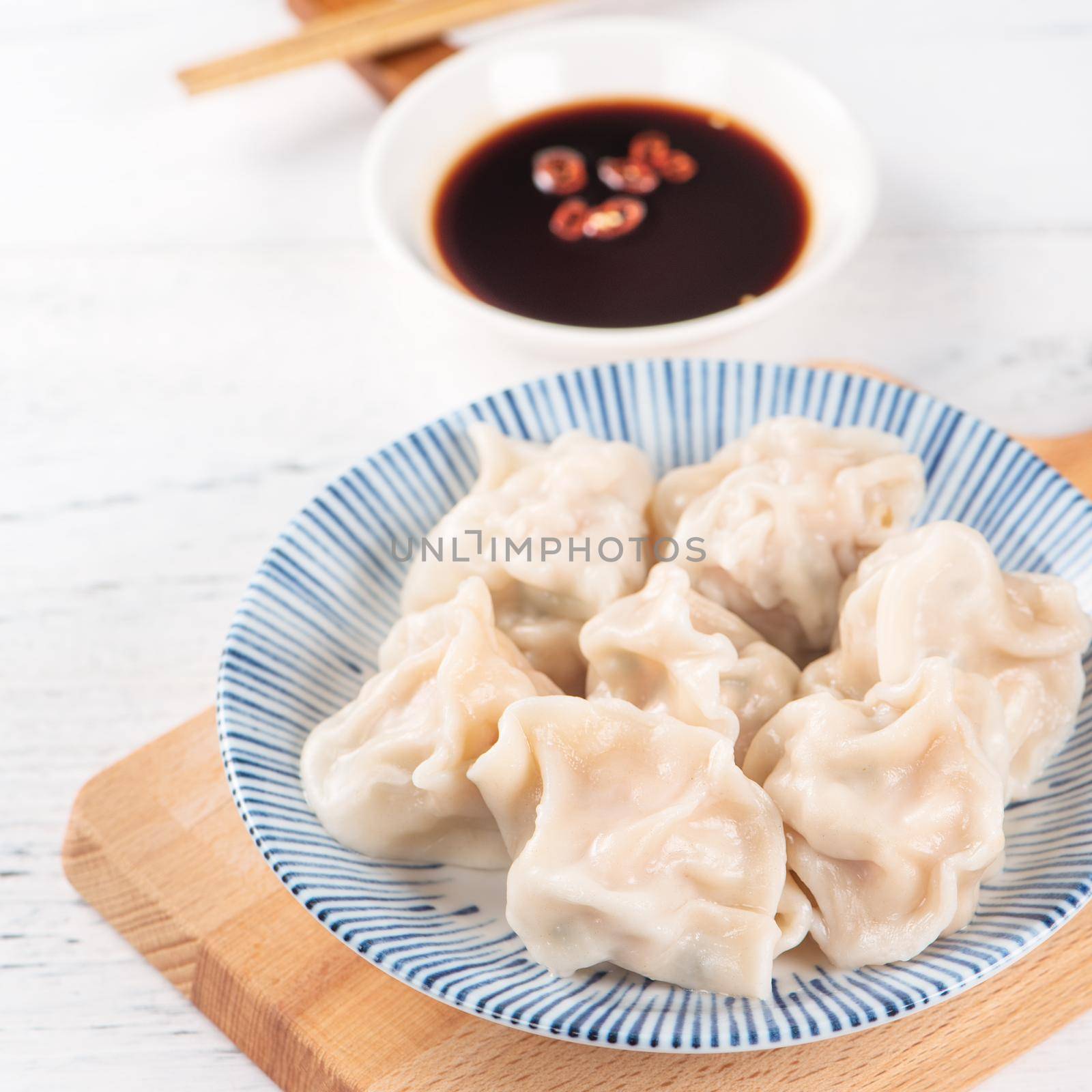 Fresh, delicious boiled pork gyoza dumplings, jiaozi on white background with soy sauce and chopsticks, close up, lifestyle. Homemade design concept. by ROMIXIMAGE