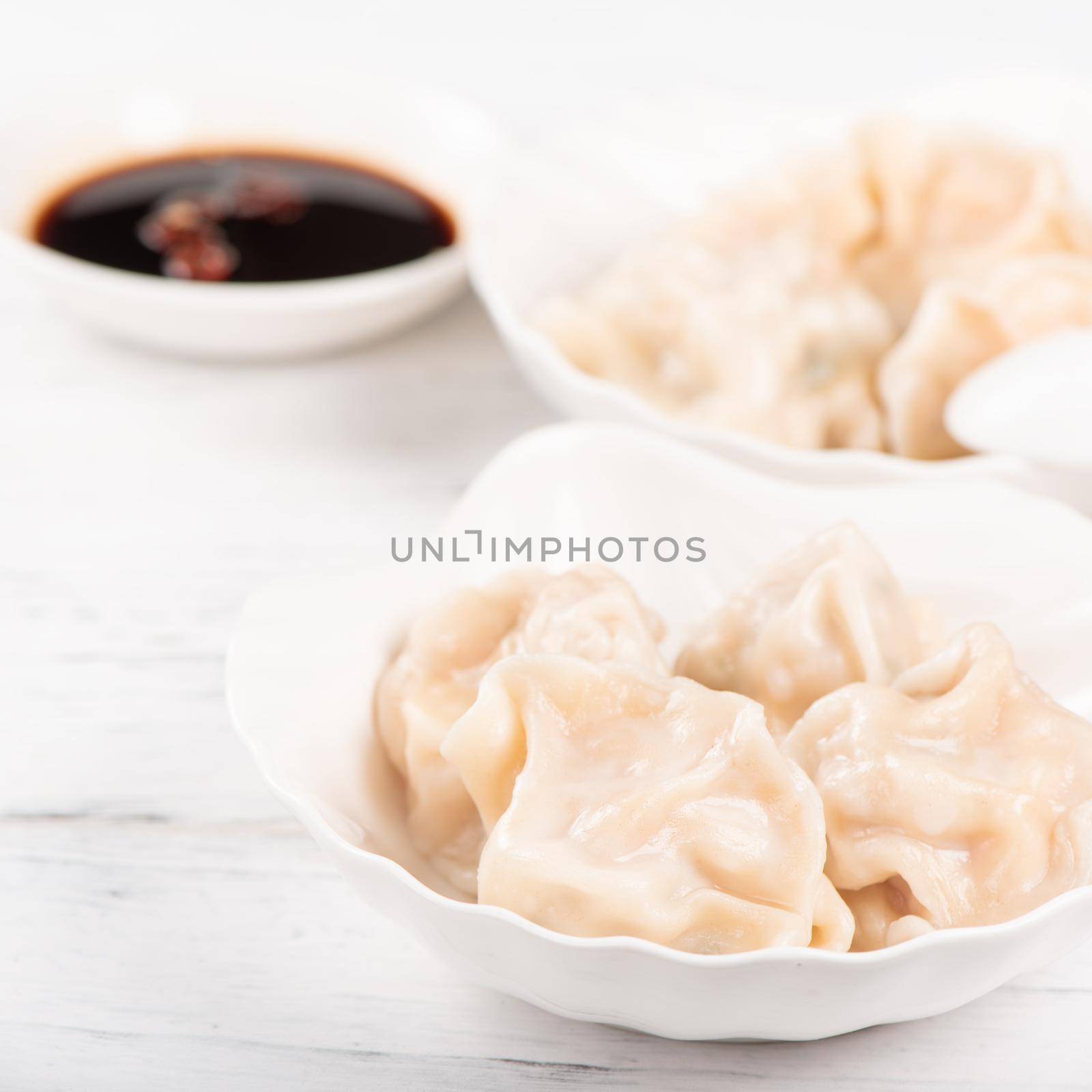 Fresh, delicious boiled pork gyoza dumplings, jiaozi on white background with soy sauce and chopsticks, close up, lifestyle. Homemade design concept. by ROMIXIMAGE