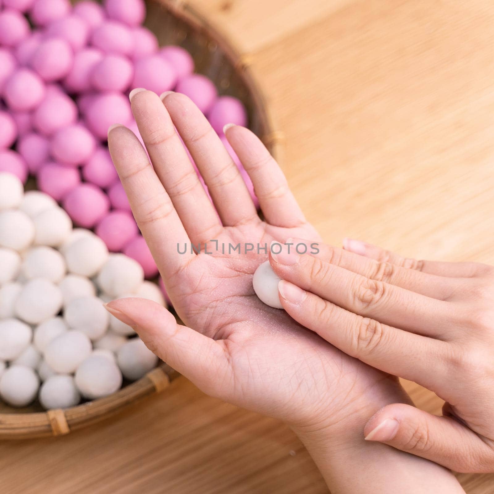 An Asia woman is making Tang yuan, yuan xiao, Chinese traditional food rice dumplings in red and white for lunar new year, winter festival, close up.