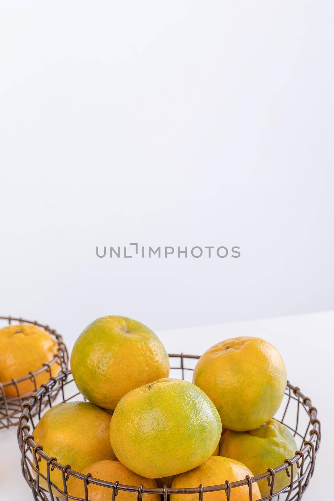 Beautiful peeled tangerines in a plate and metal basket isolated on bright white clean table in a modern contemporary kitchen island, close up.