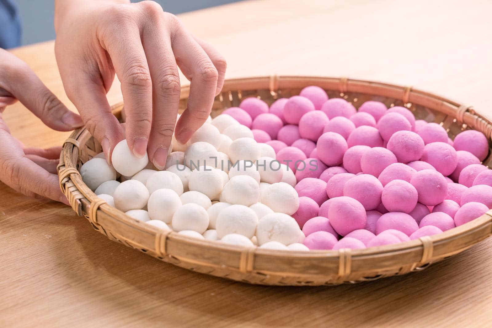 An Asia woman is making Tang yuan, yuan xiao, Chinese traditional food rice dumplings in red and white for lunar new year, winter festival, close up.