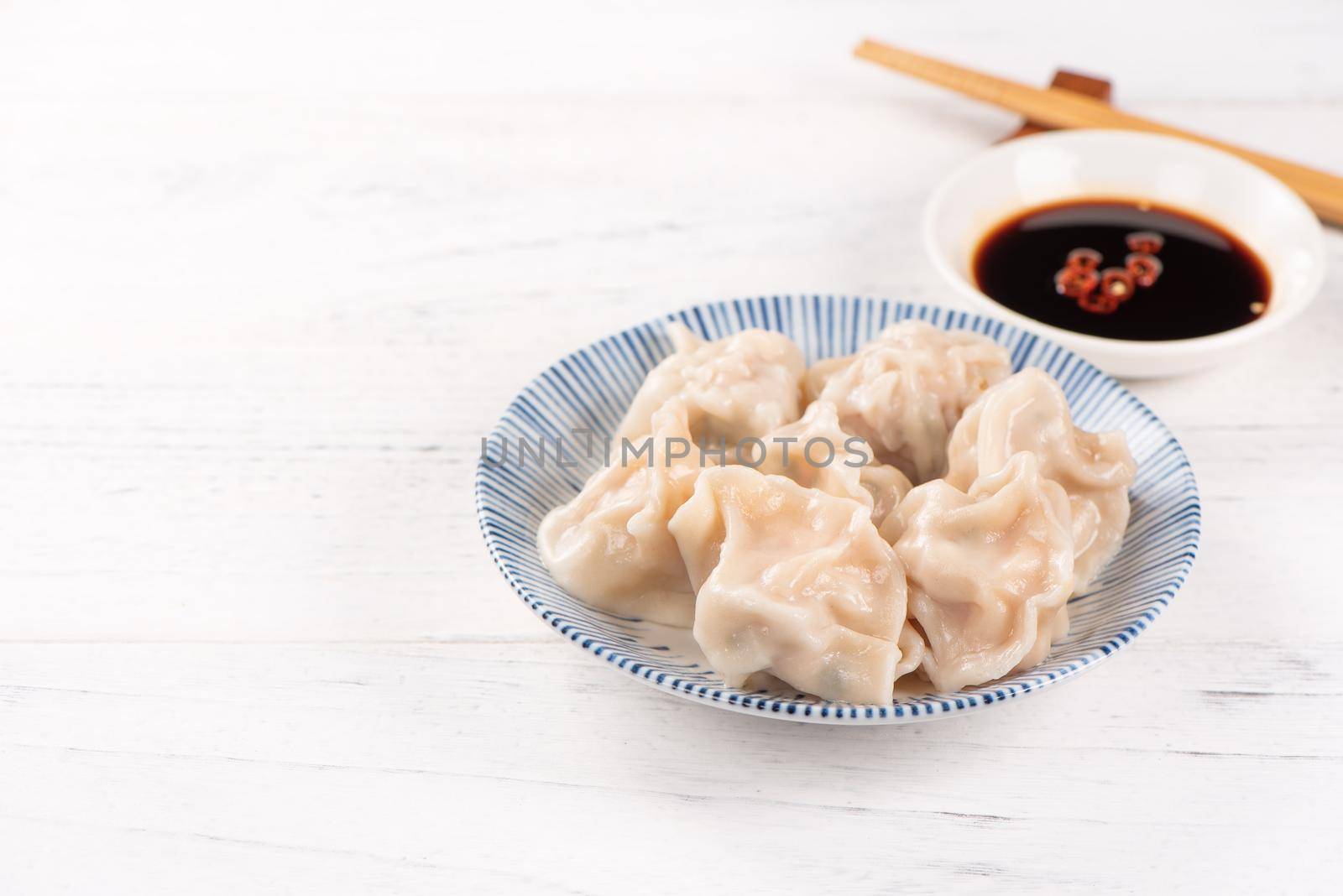Fresh, delicious boiled pork gyoza dumplings, jiaozi on white background with soy sauce and chopsticks, close up, lifestyle. Homemade design concept.