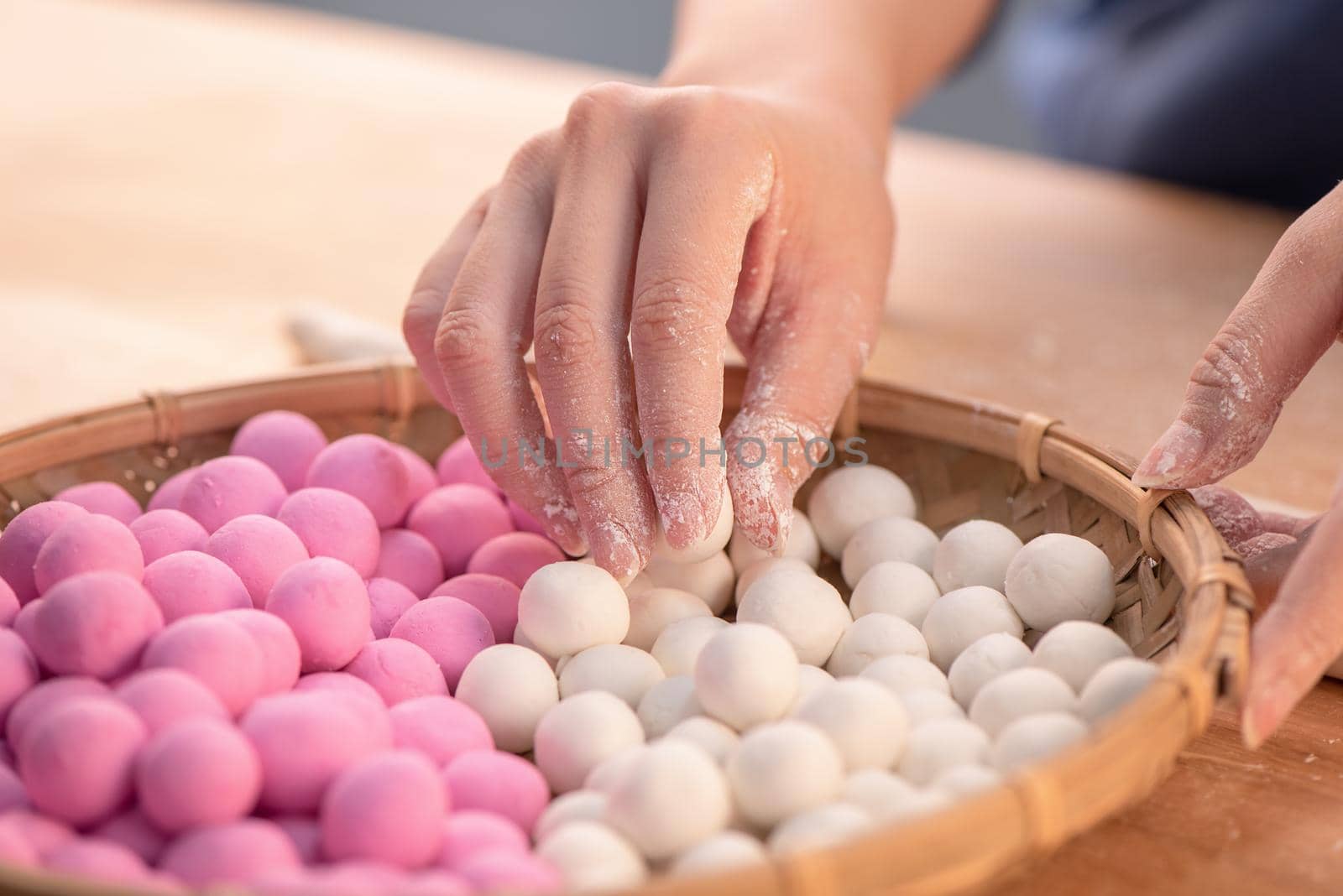 An Asia woman is making Tang yuan, yuan xiao, Chinese traditional food rice dumplings in red and white for lunar new year, winter festival, close up.