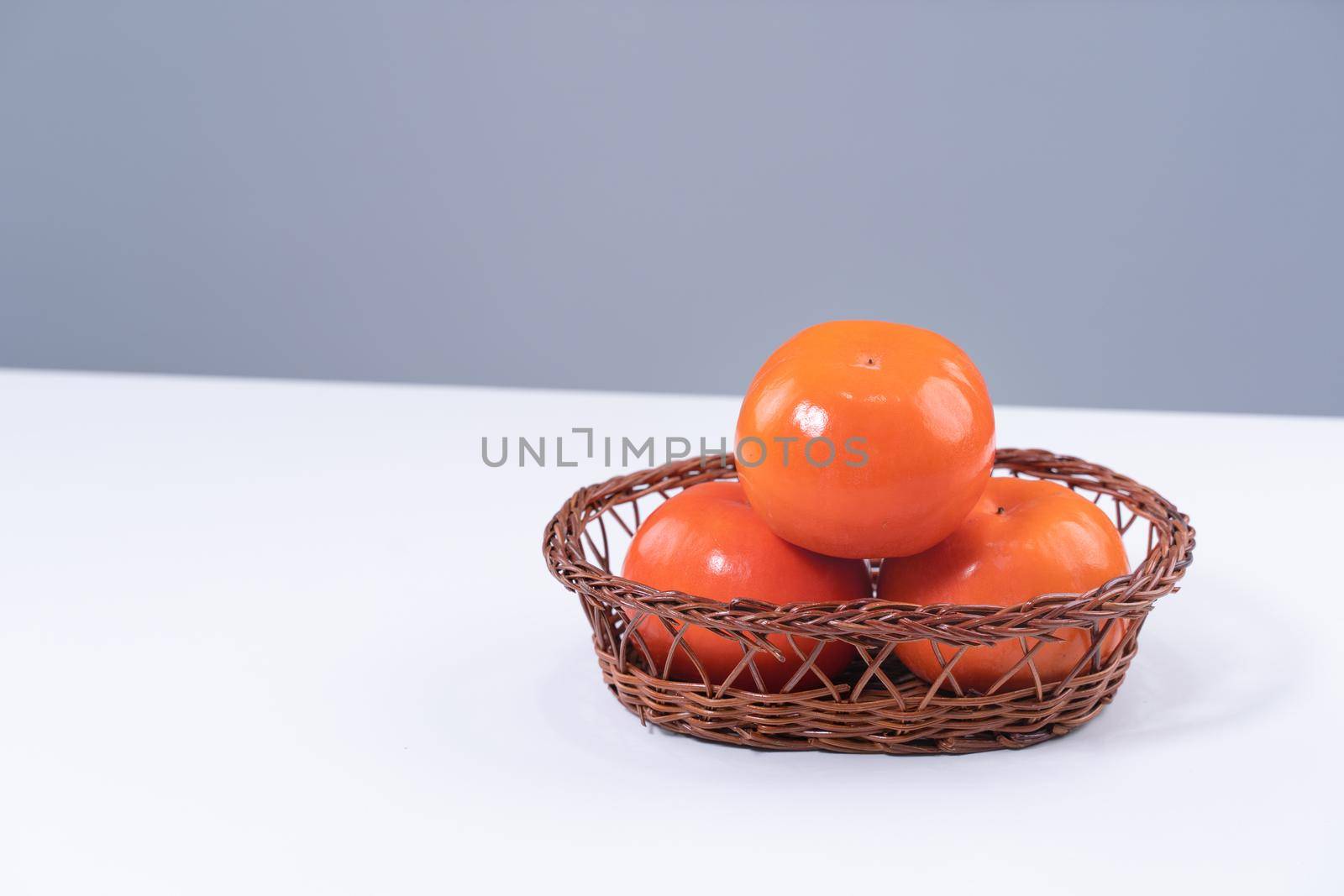 Fresh beautiful sliced sweet persimmon kaki isolated on white kitchen table with gray blue background, Chinese lunar new year design concept, close up.