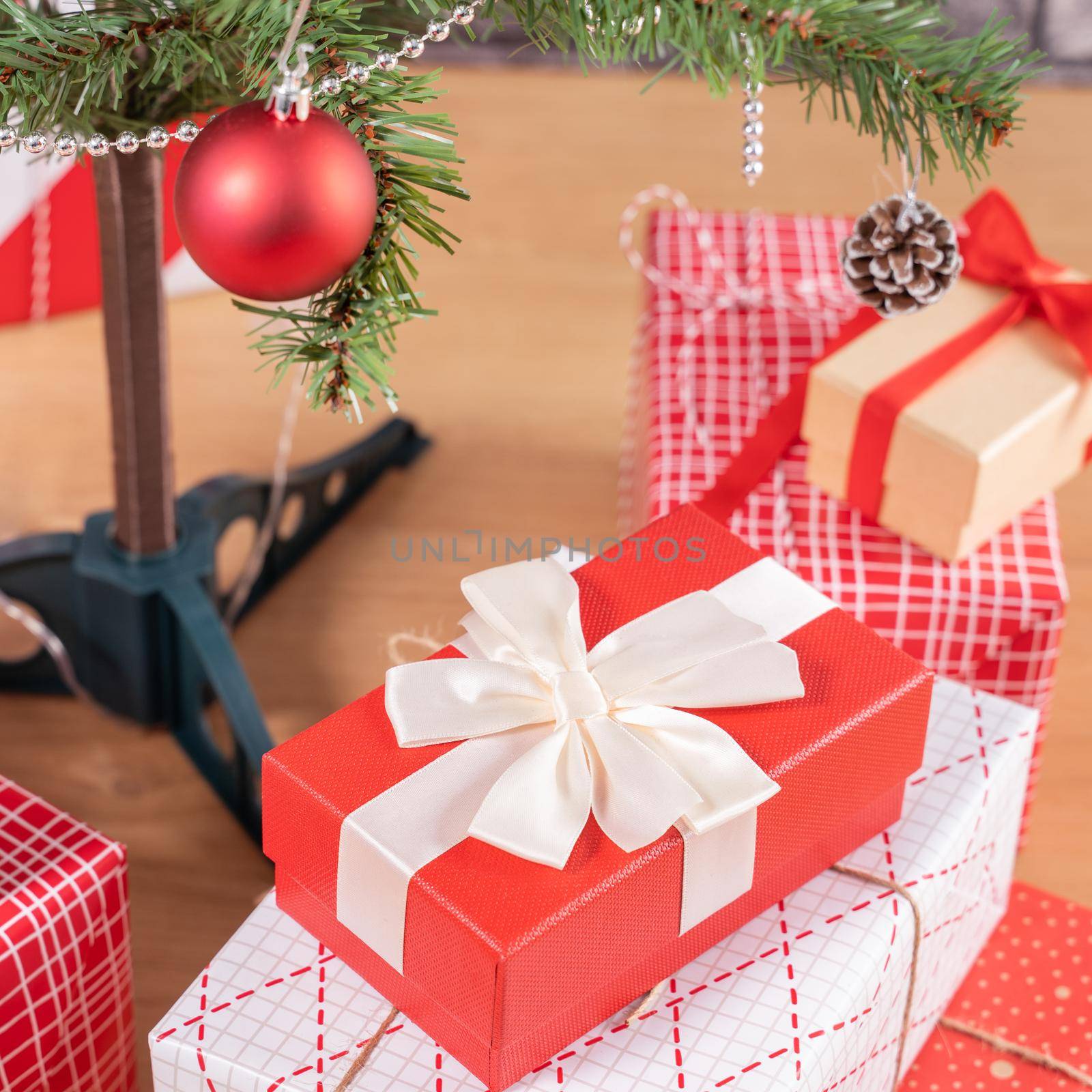 Decorated Christmas tree with wrapped beautiful red and white gifts at home with black brick wall, festive design concept, close up. by ROMIXIMAGE