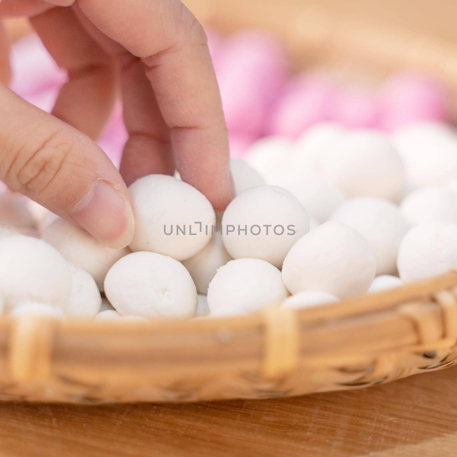 An Asia woman is making Tang yuan, yuan xiao, Chinese traditional food rice dumplings in red and white for lunar new year, winter festival, close up. by ROMIXIMAGE