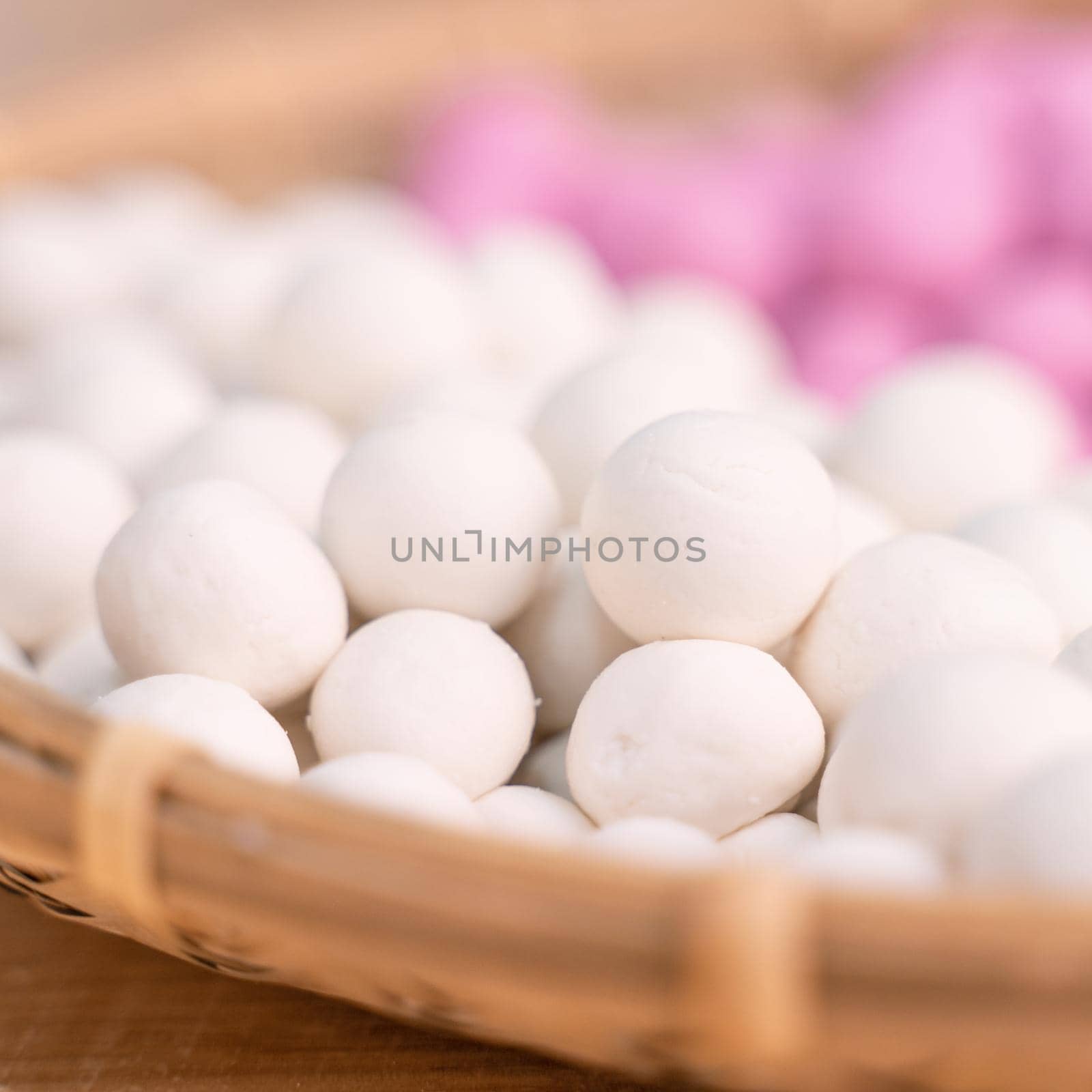 An Asia woman is making Tang yuan, yuan xiao, Chinese traditional food rice dumplings in red and white for lunar new year, winter festival, close up. by ROMIXIMAGE