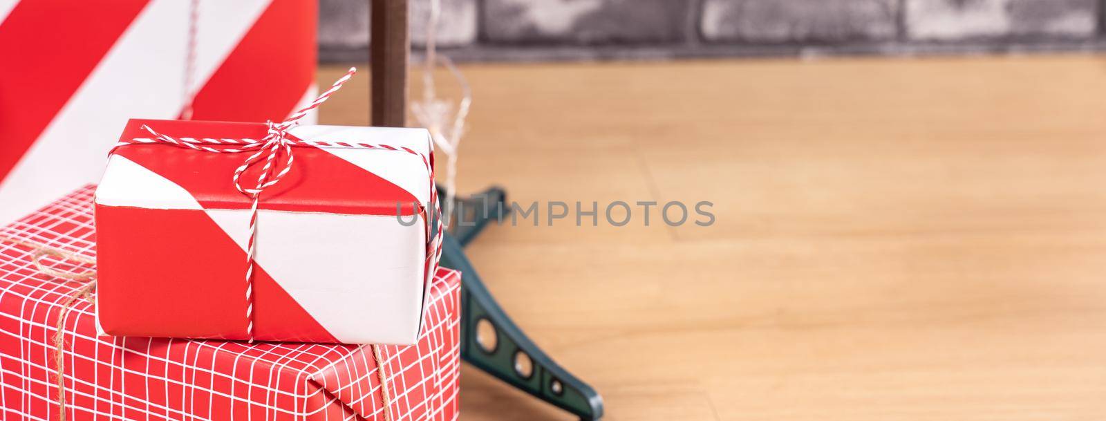 Decorated Christmas tree with wrapped beautiful red and white gifts at home with black brick wall, festive design concept, close up. by ROMIXIMAGE