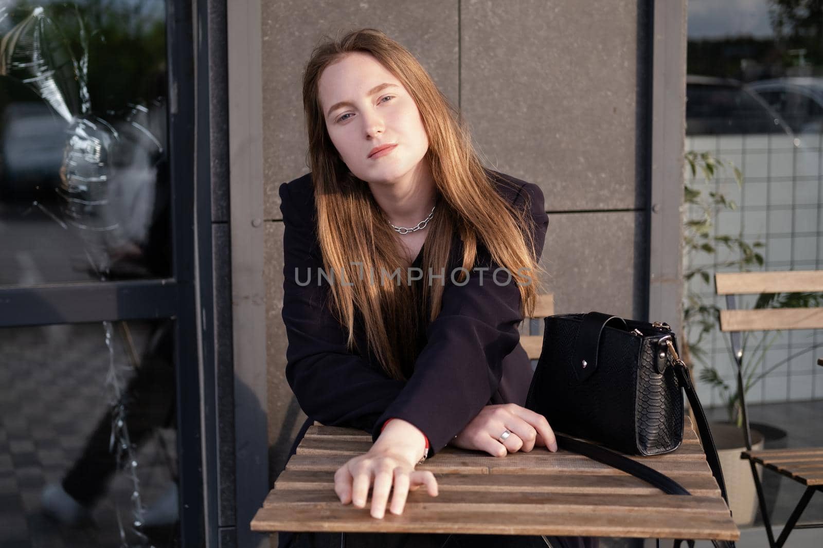 pretty brunette woman sitting by wooden table outside. feminine. millennial people. lady on coffee break.