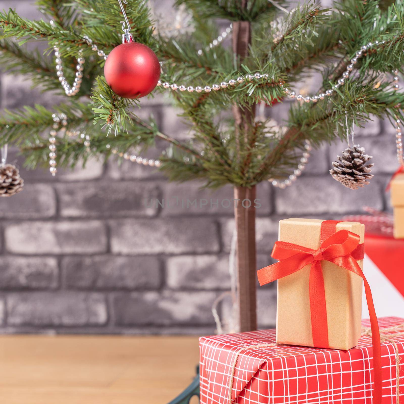 Decorated Christmas tree with wrapped beautiful red and white gifts at home with black brick wall, festive design concept, close up.