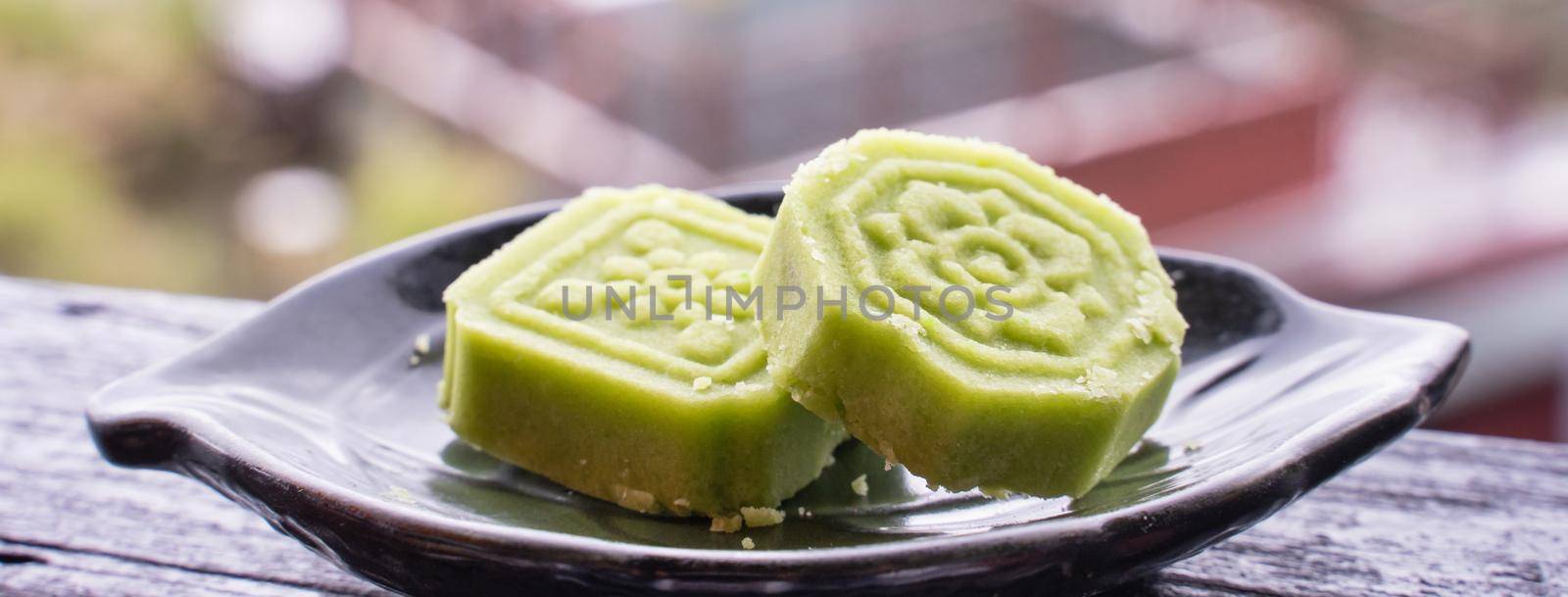 Delicious green mung bean cake with black tea plate on wooden railing of a teahouse in Taiwan with beautiful landscape in background, close up.