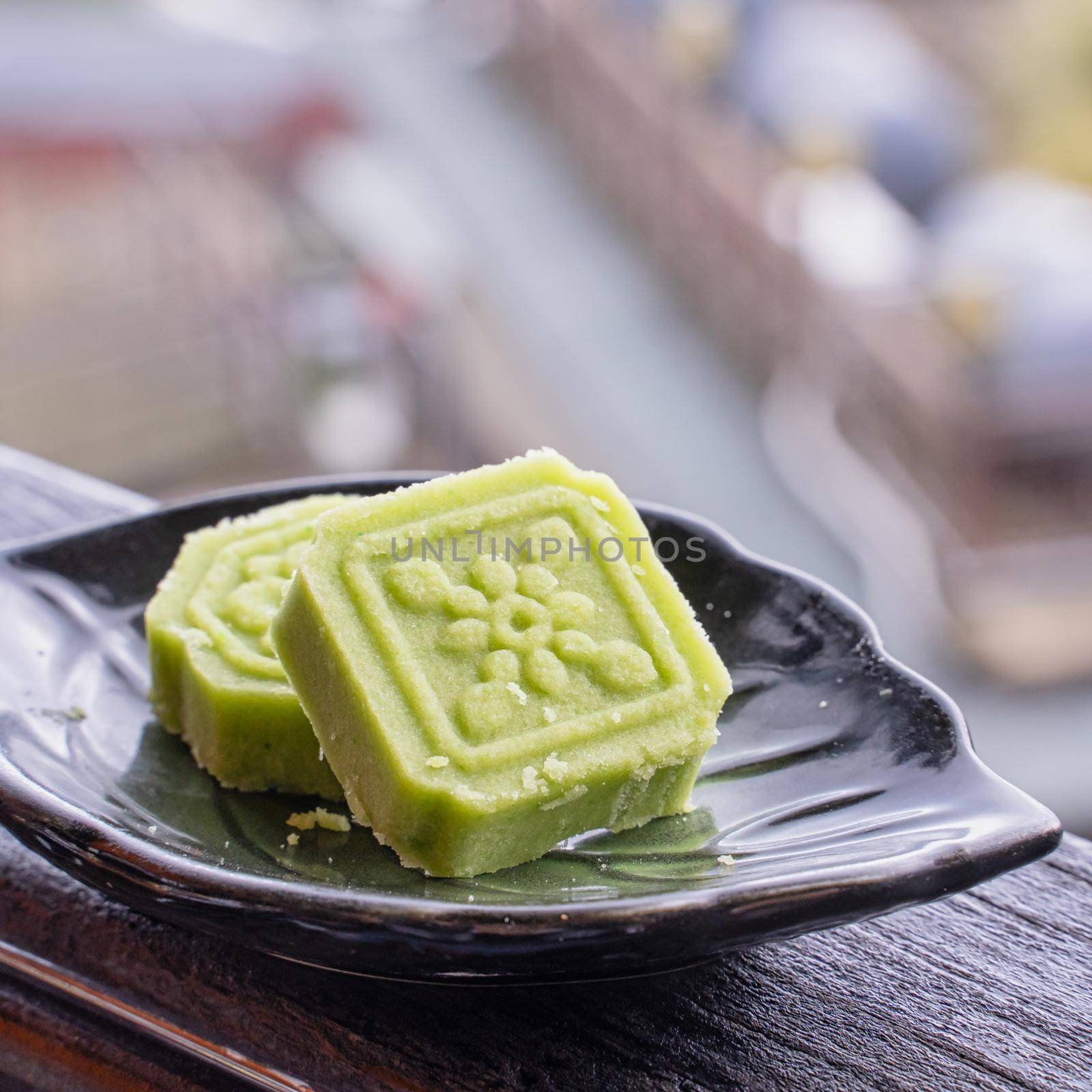 Delicious green mung bean cake with black tea plate on wooden railing of a teahouse in Taiwan with beautiful landscape in background, close up. by ROMIXIMAGE