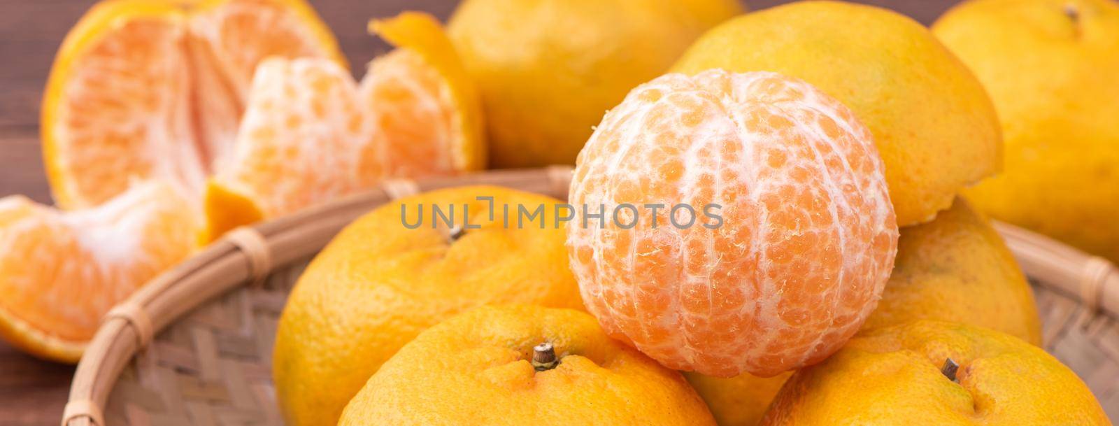 Fresh, beautiful orange color tangerine on bamboo sieve over dark wooden table. Seasonal, traditional fruit of Chinese lunar new year, close up.
