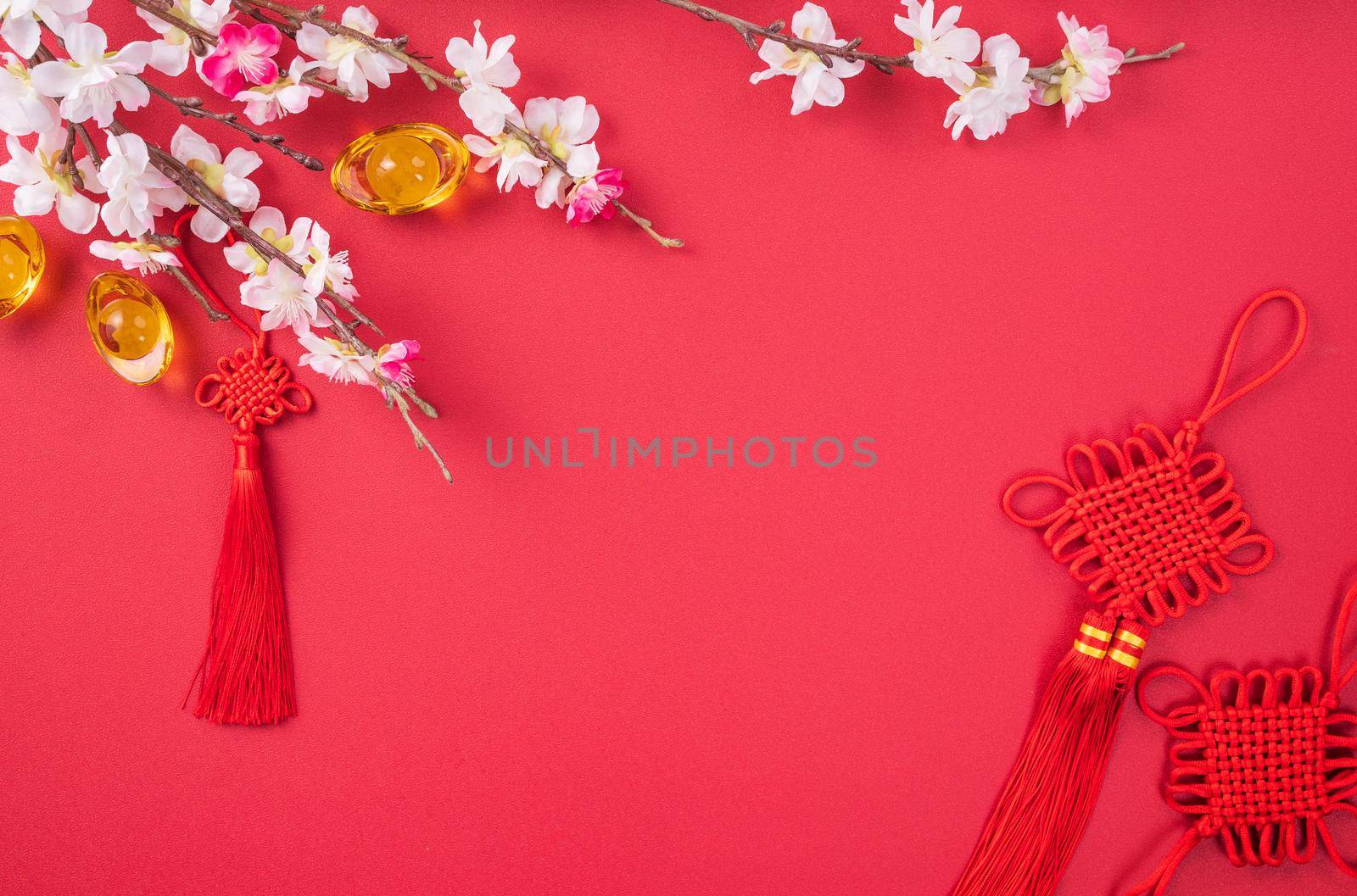 Design concept of Chinese lunar new year - Beautiful Chinese knot with plum blossom isolated on red background, flat lay, top view, overhead layout.