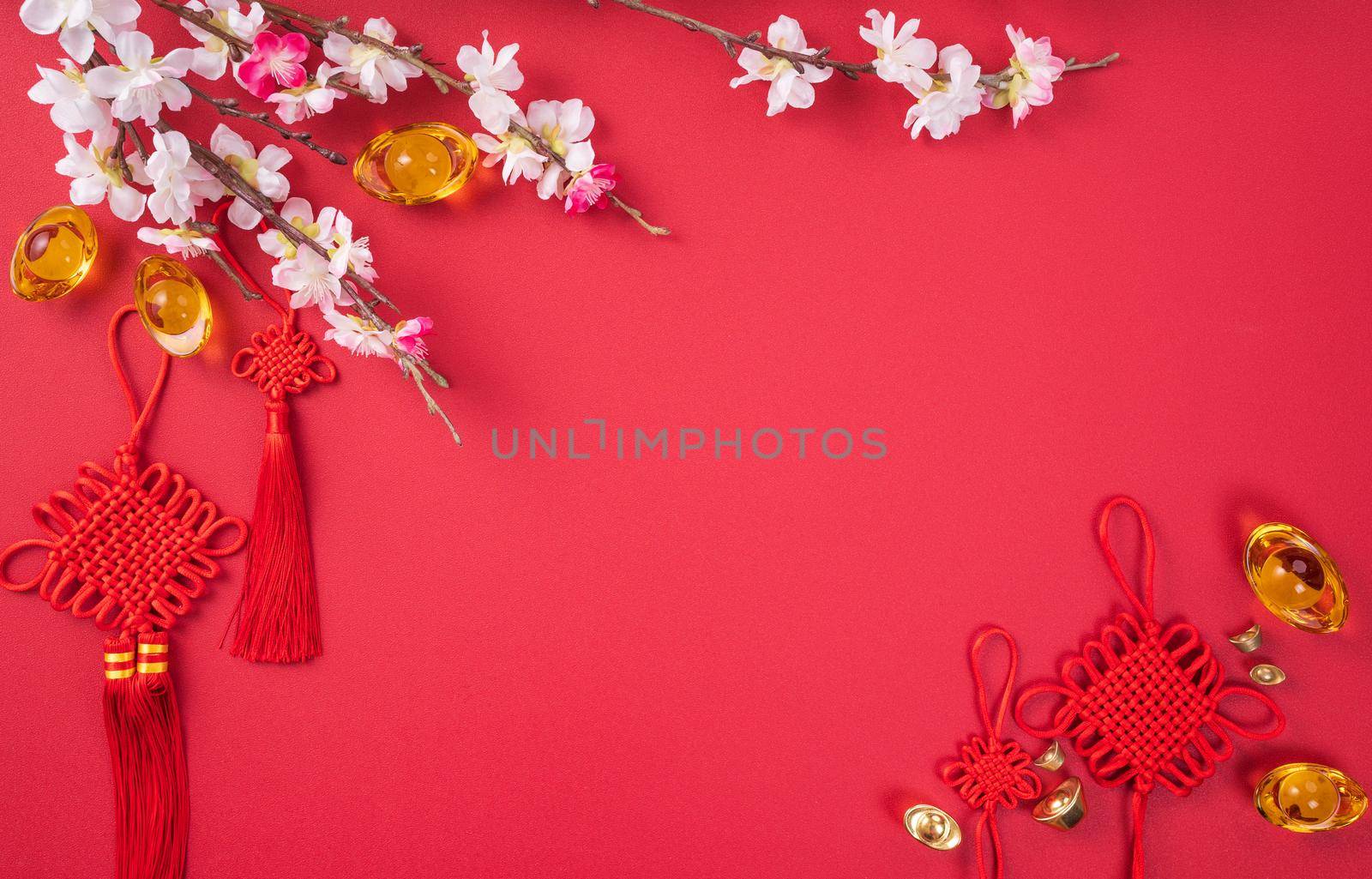 Design concept of Chinese lunar new year - Beautiful Chinese knot with plum blossom isolated on red background, flat lay, top view, overhead layout.
