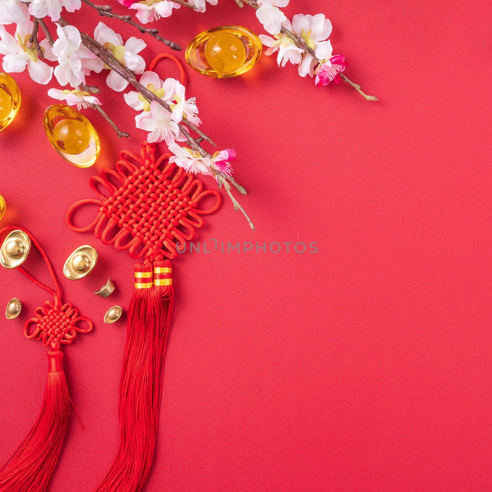 Design concept of Chinese lunar new year - Beautiful Chinese knot with plum blossom isolated on red background, flat lay, top view, overhead layout. by ROMIXIMAGE